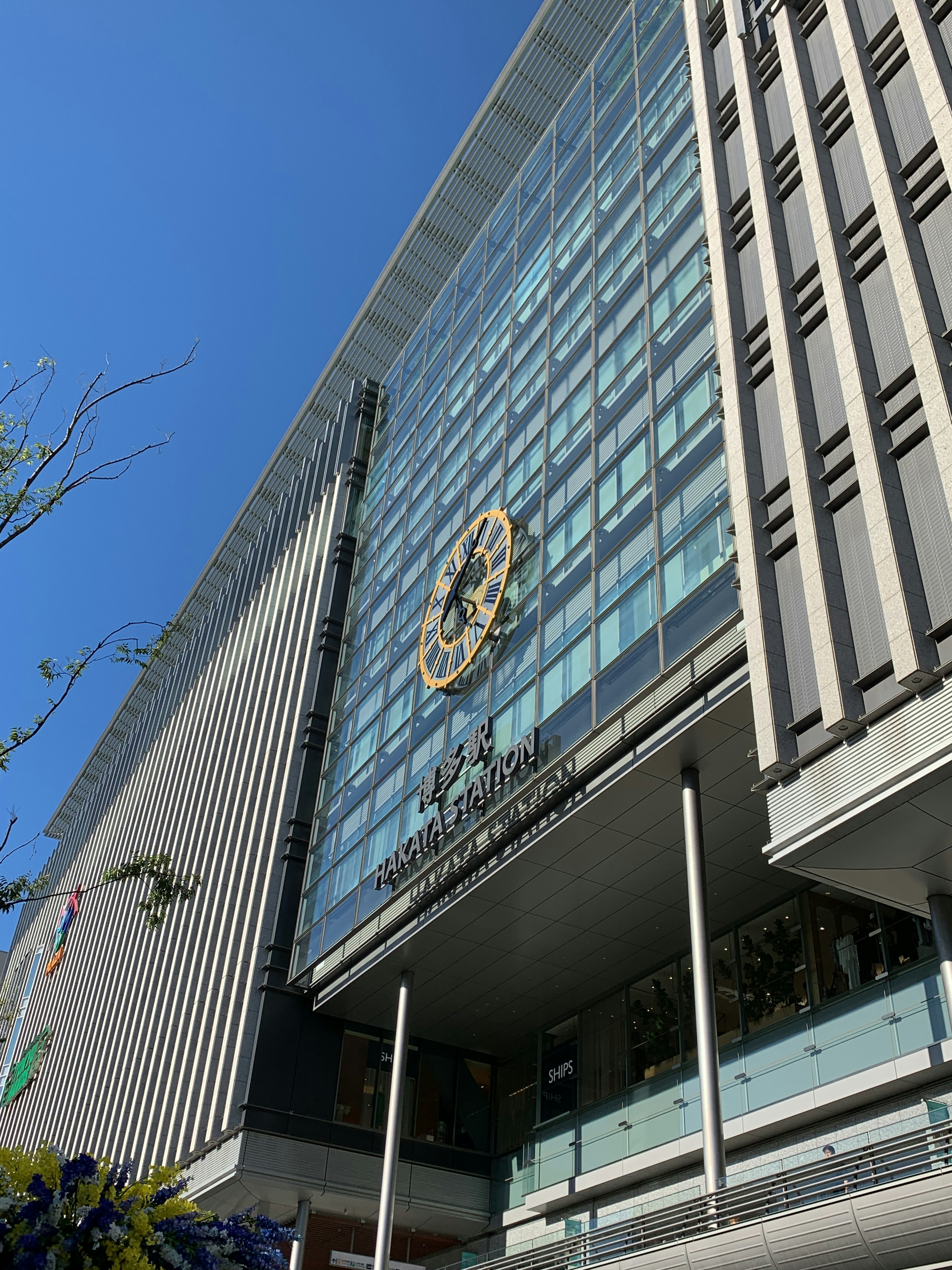 Exterior de un edificio moderno bajo un cielo azul fachada de vidrio con un logo redondo prominente