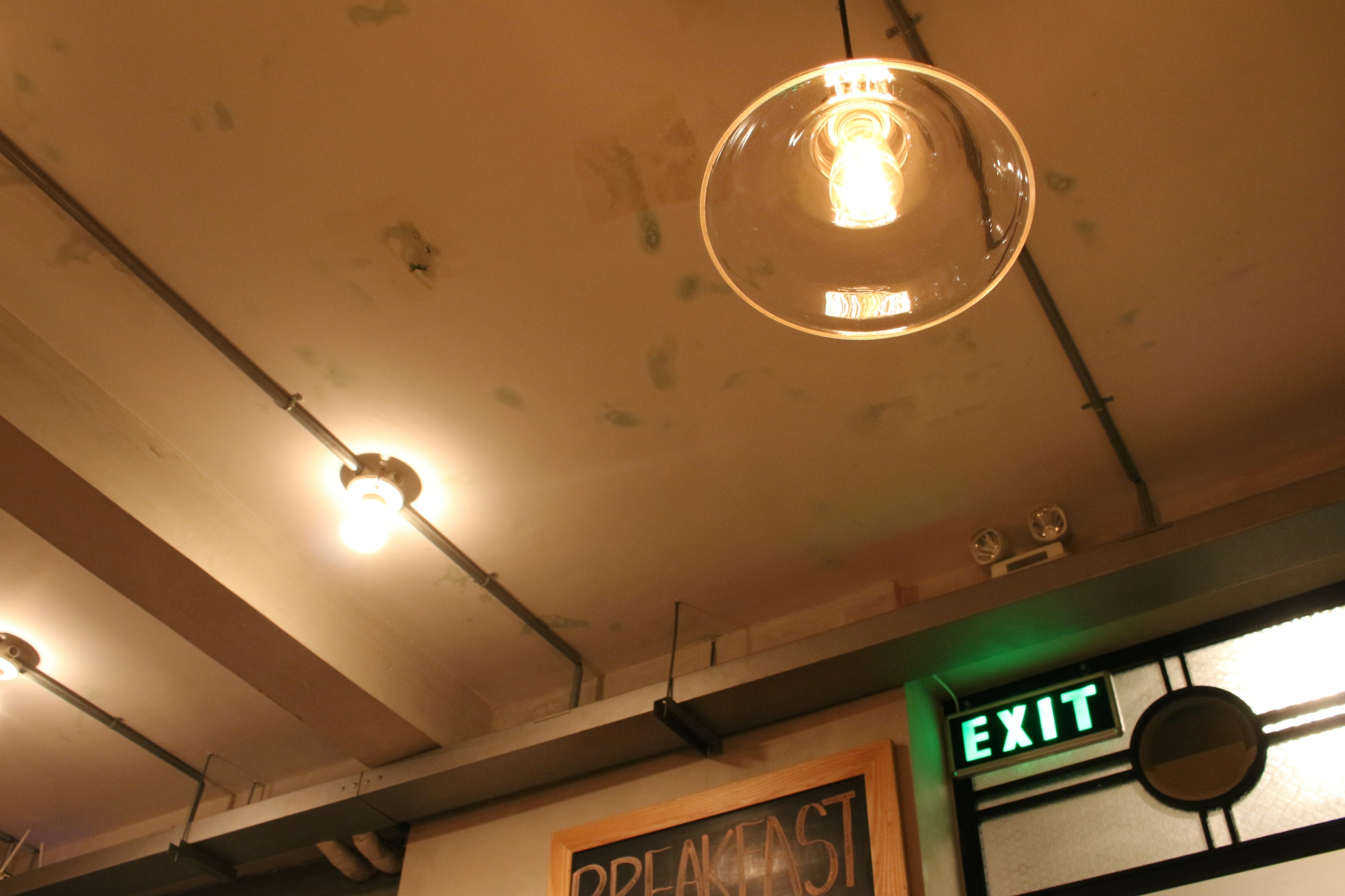 Interior of a cafe with bright lighting and an exit sign