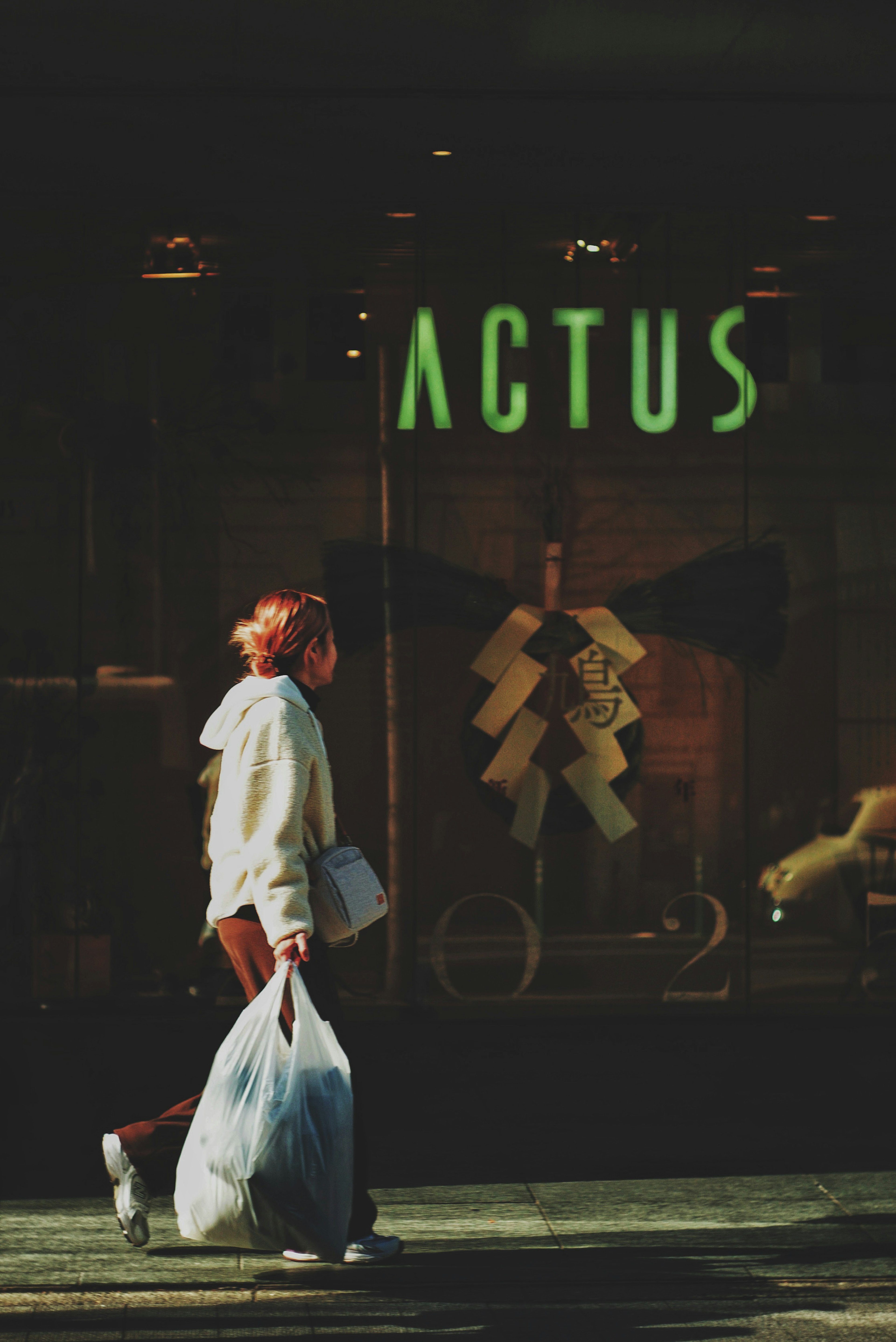 Mujer llevando una bolsa de basura caminando frente a la tienda ACTUS