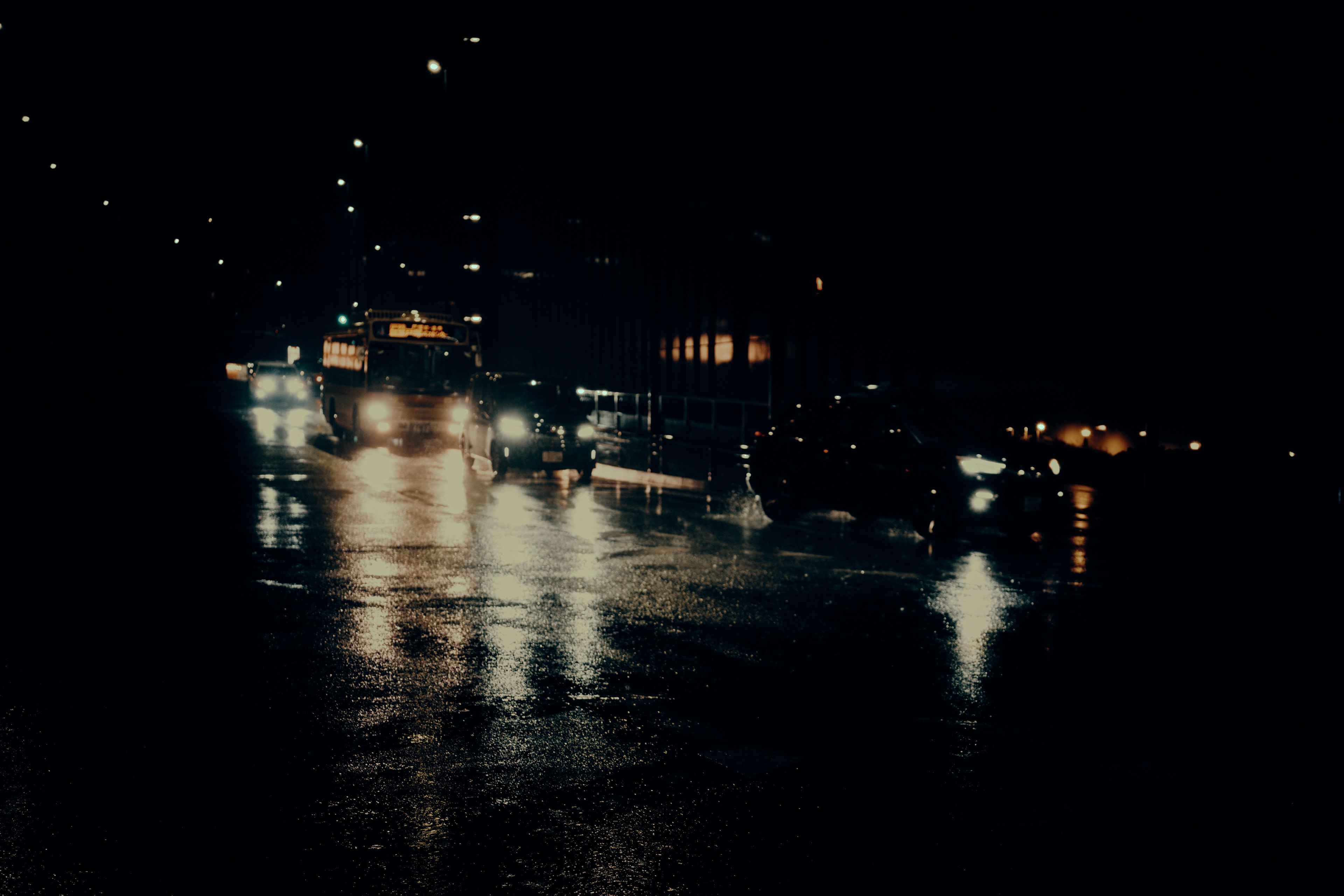 Calle de la ciudad por la noche con reflejos en charcos y luces de coches