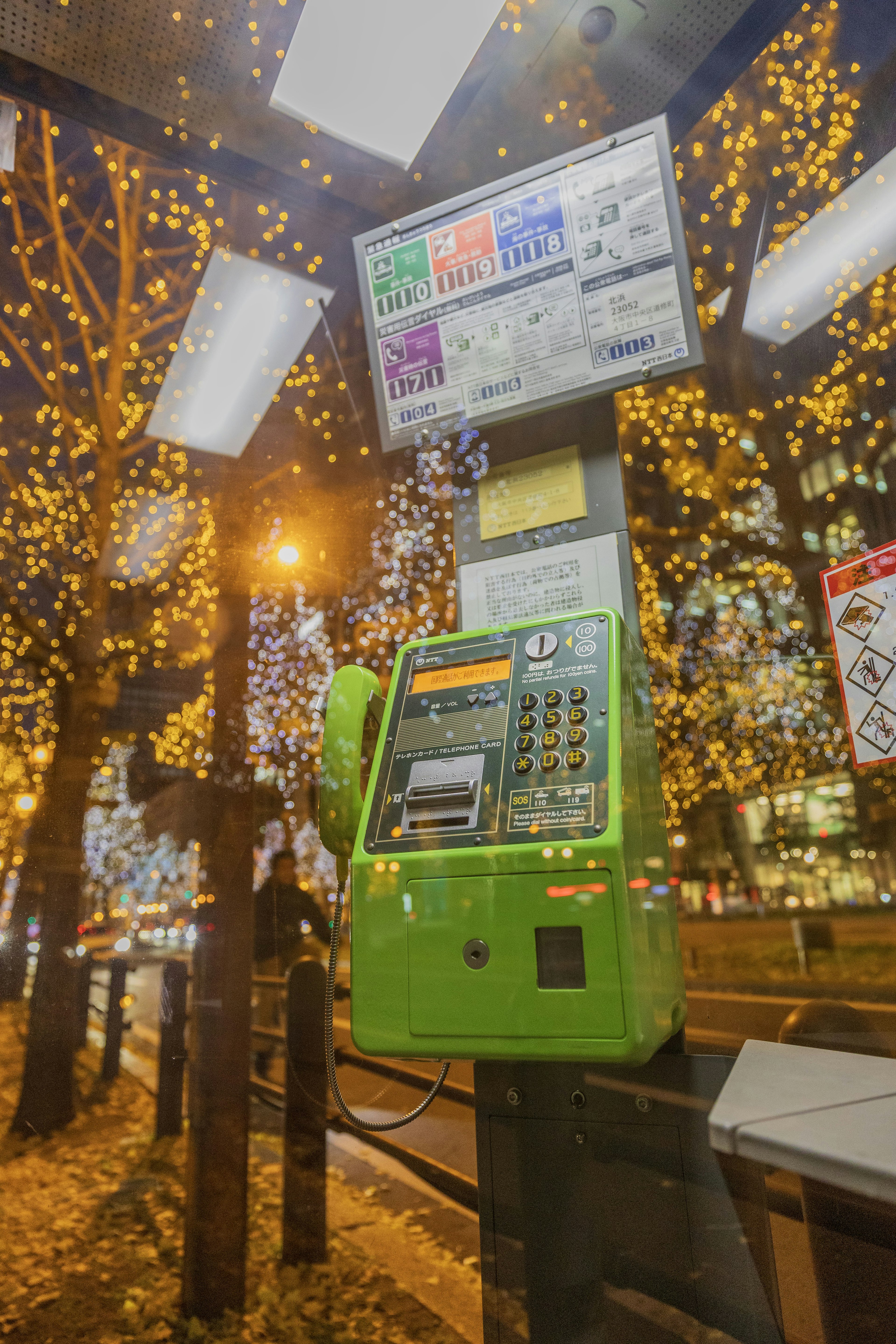 Street telephone booth illuminated by festive lights at night