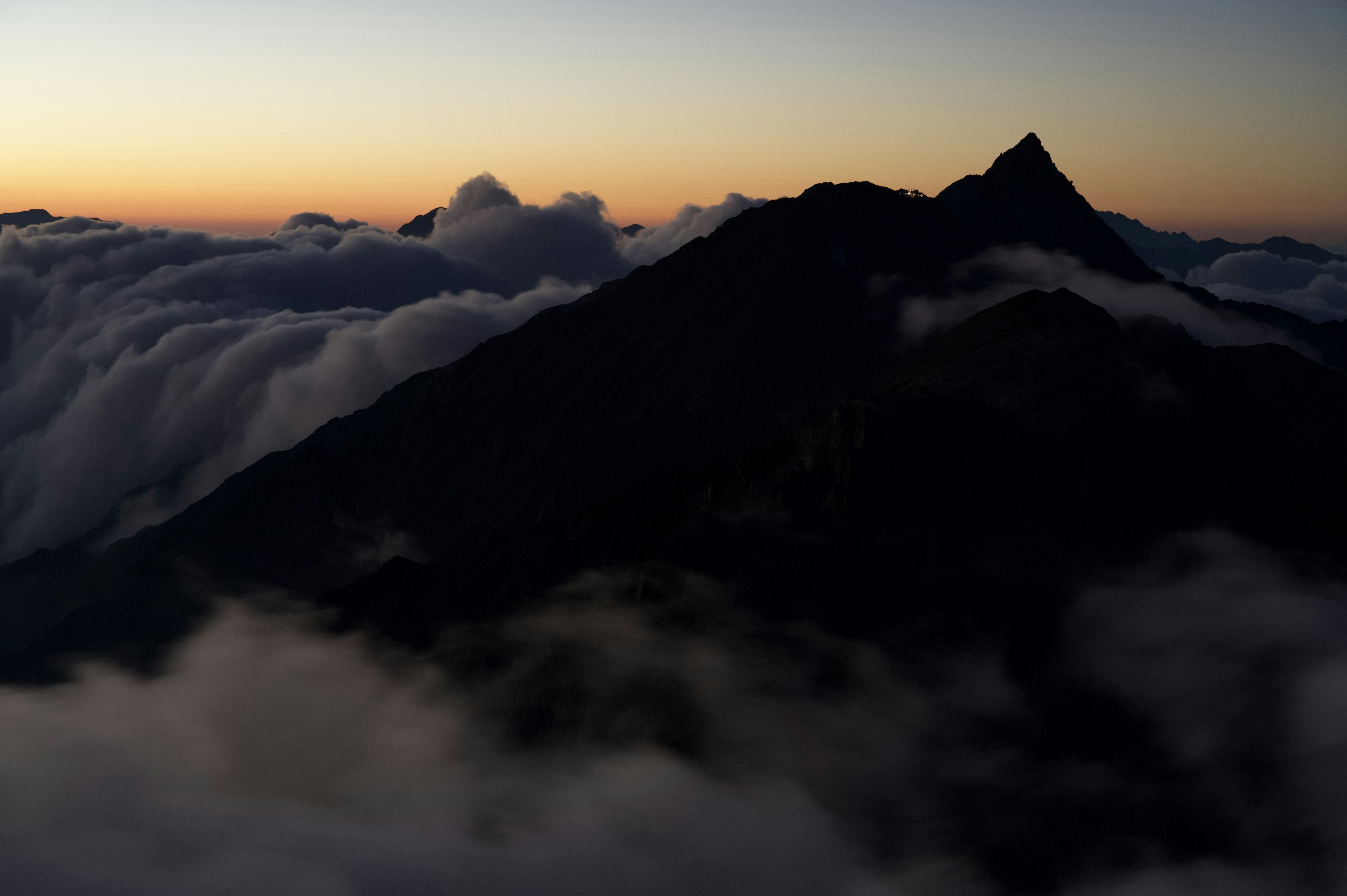 雲に覆われた山のシルエットと夕焼けの空