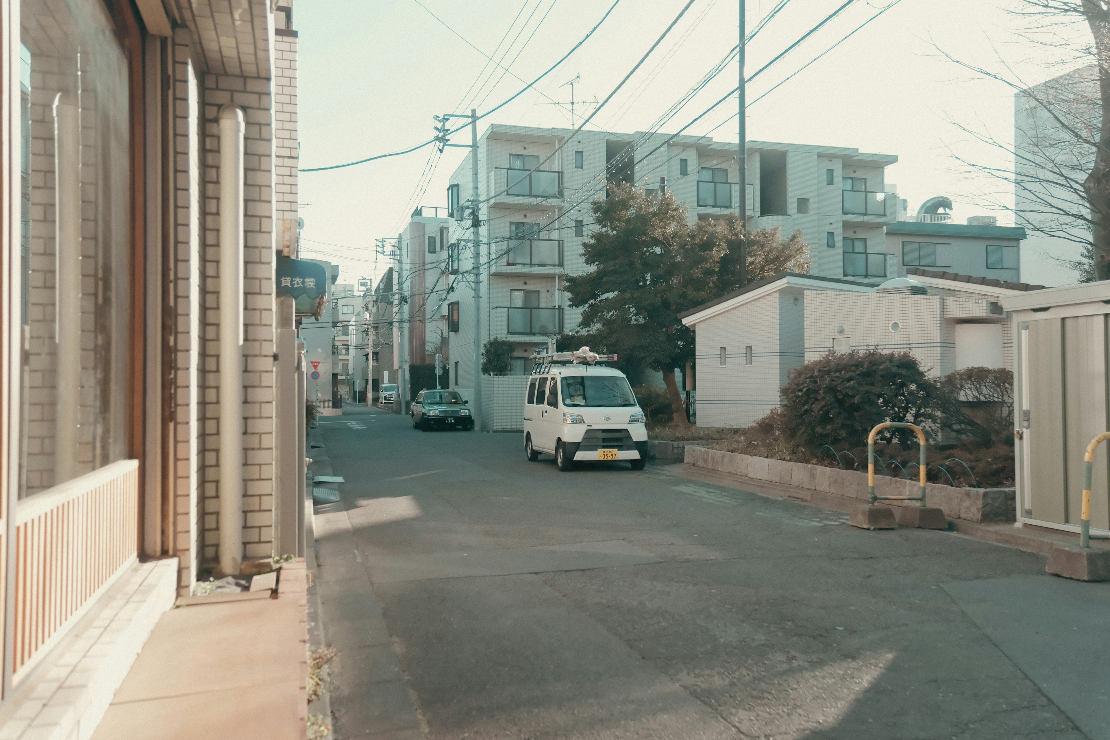 静かな街並みの風景に白いバンが止まっている