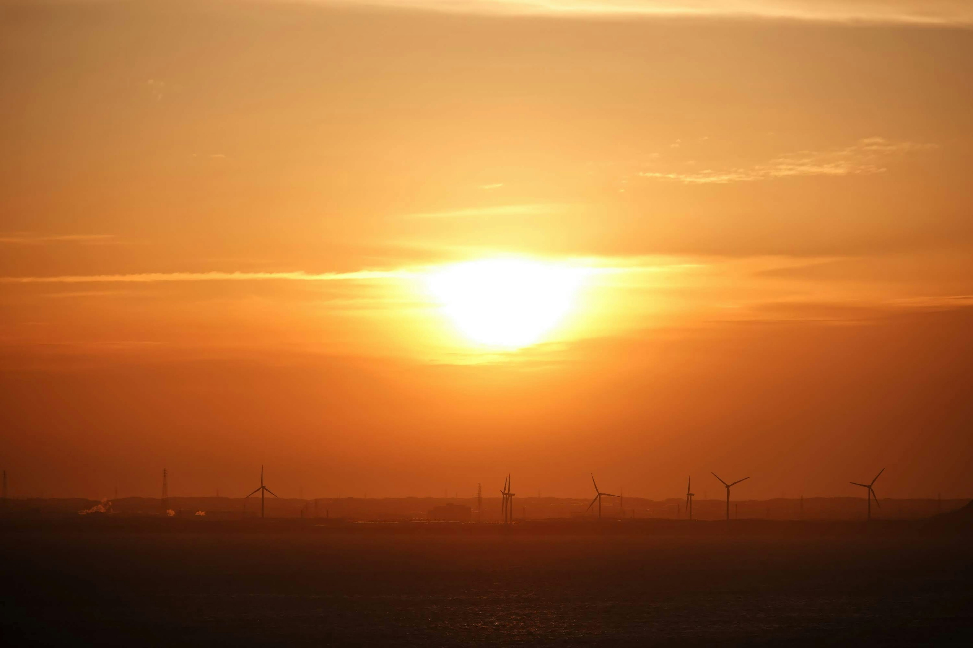 Atardecer sobre un paisaje con siluetas de turbinas eólicas