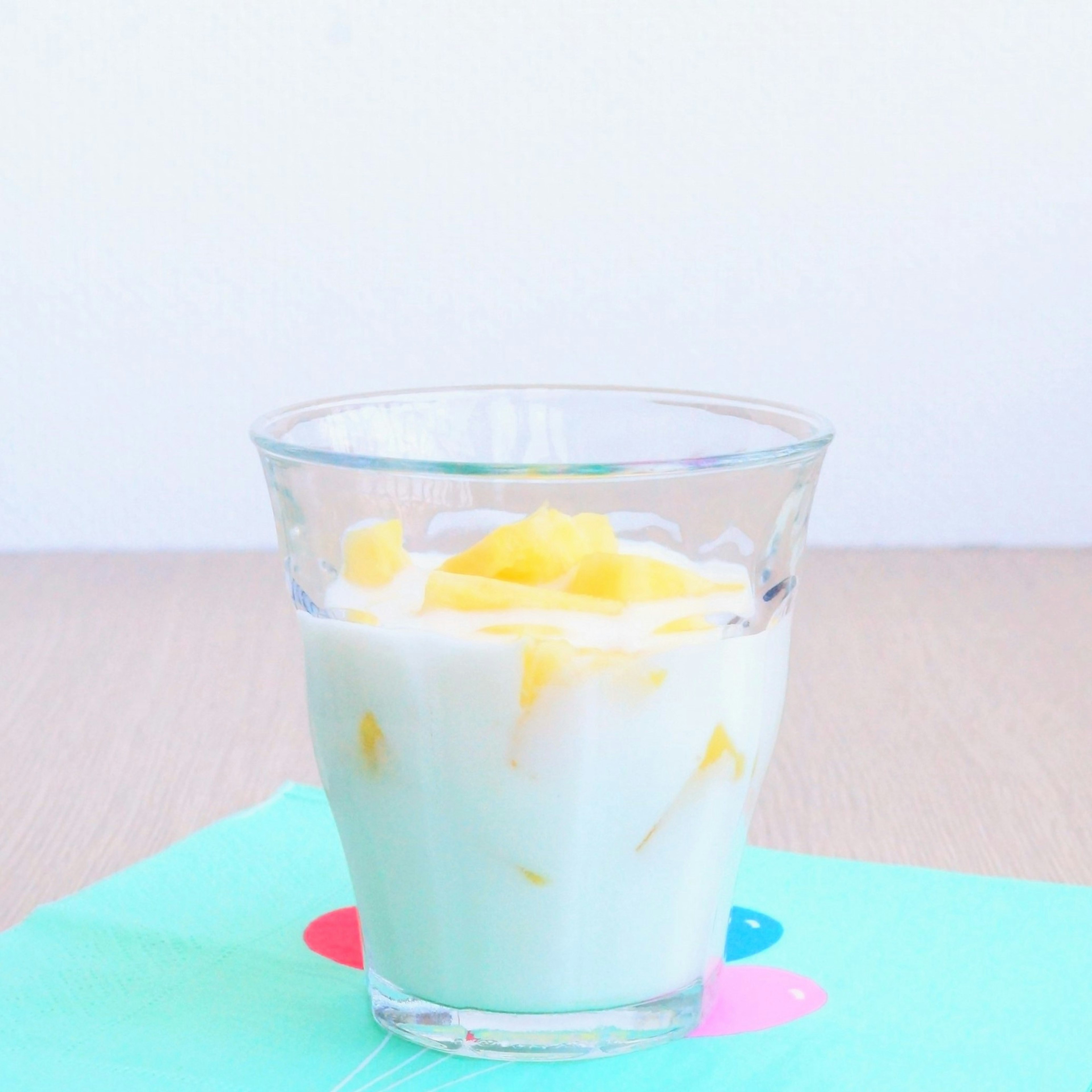 Un bicchiere di dessert allo yogurt con mango e pezzi di mango visibili