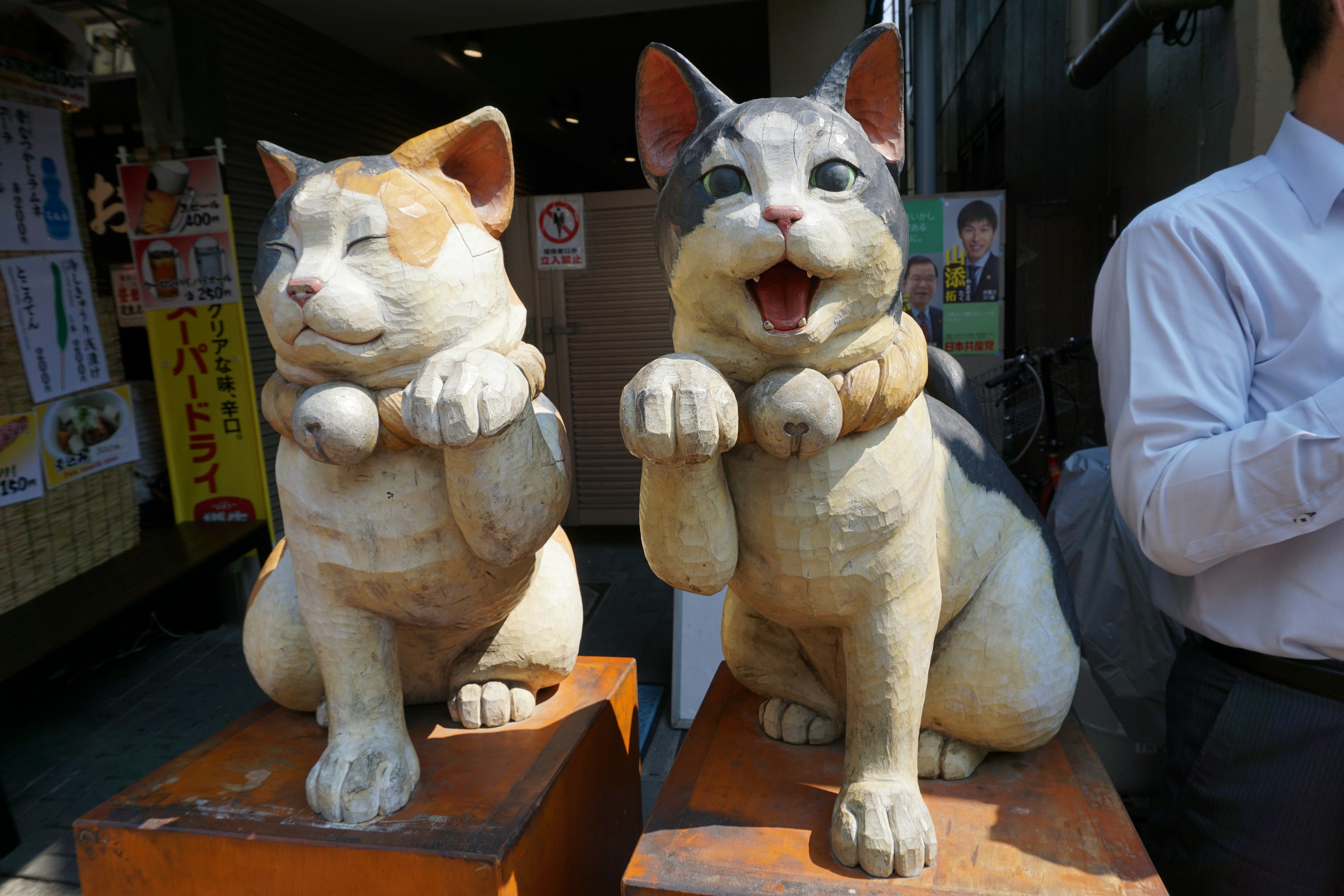 Two cat statues are standing side by side one is brown and the other has gray markings