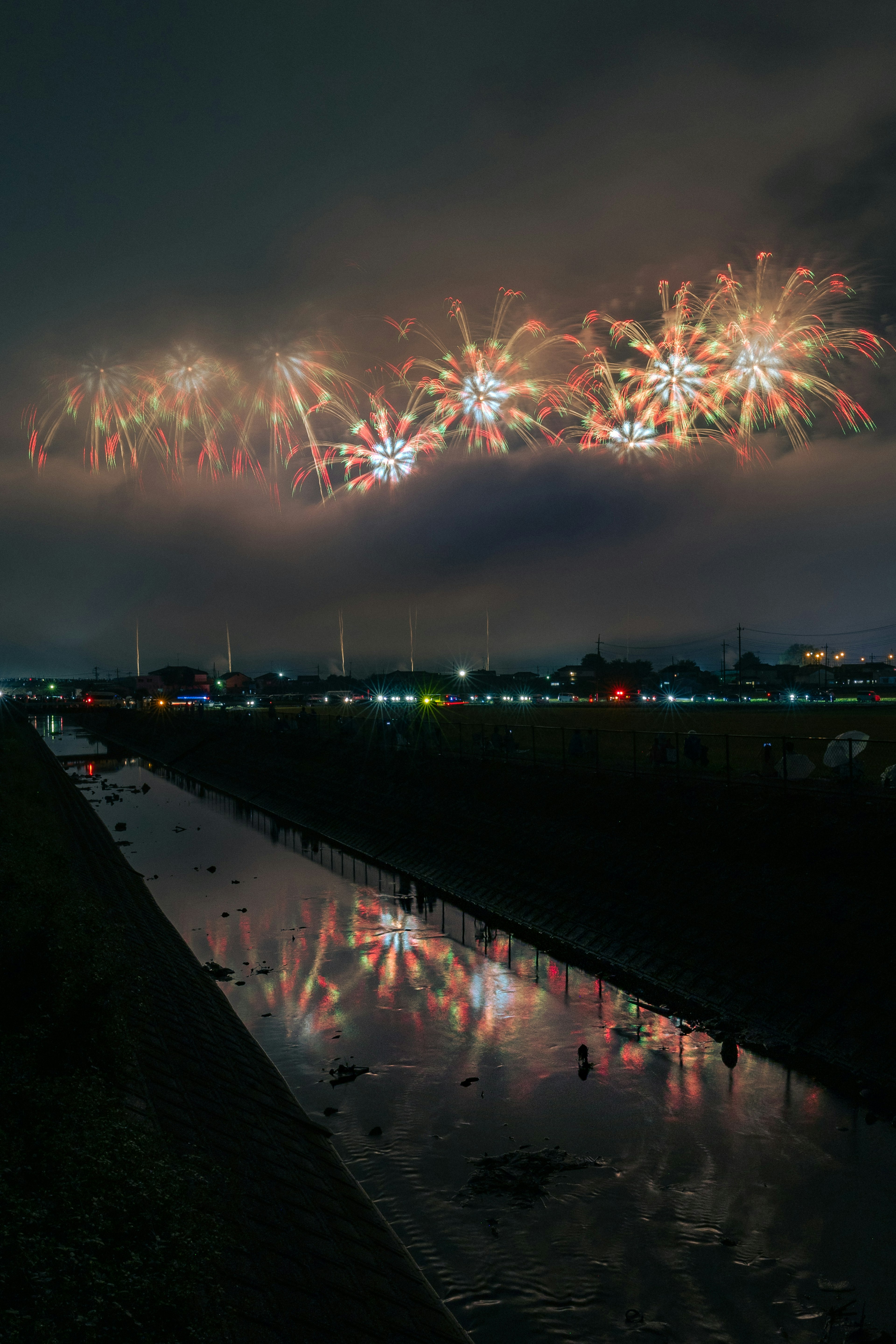 Fuegos artificiales iluminando el cielo nocturno con reflejos en el río