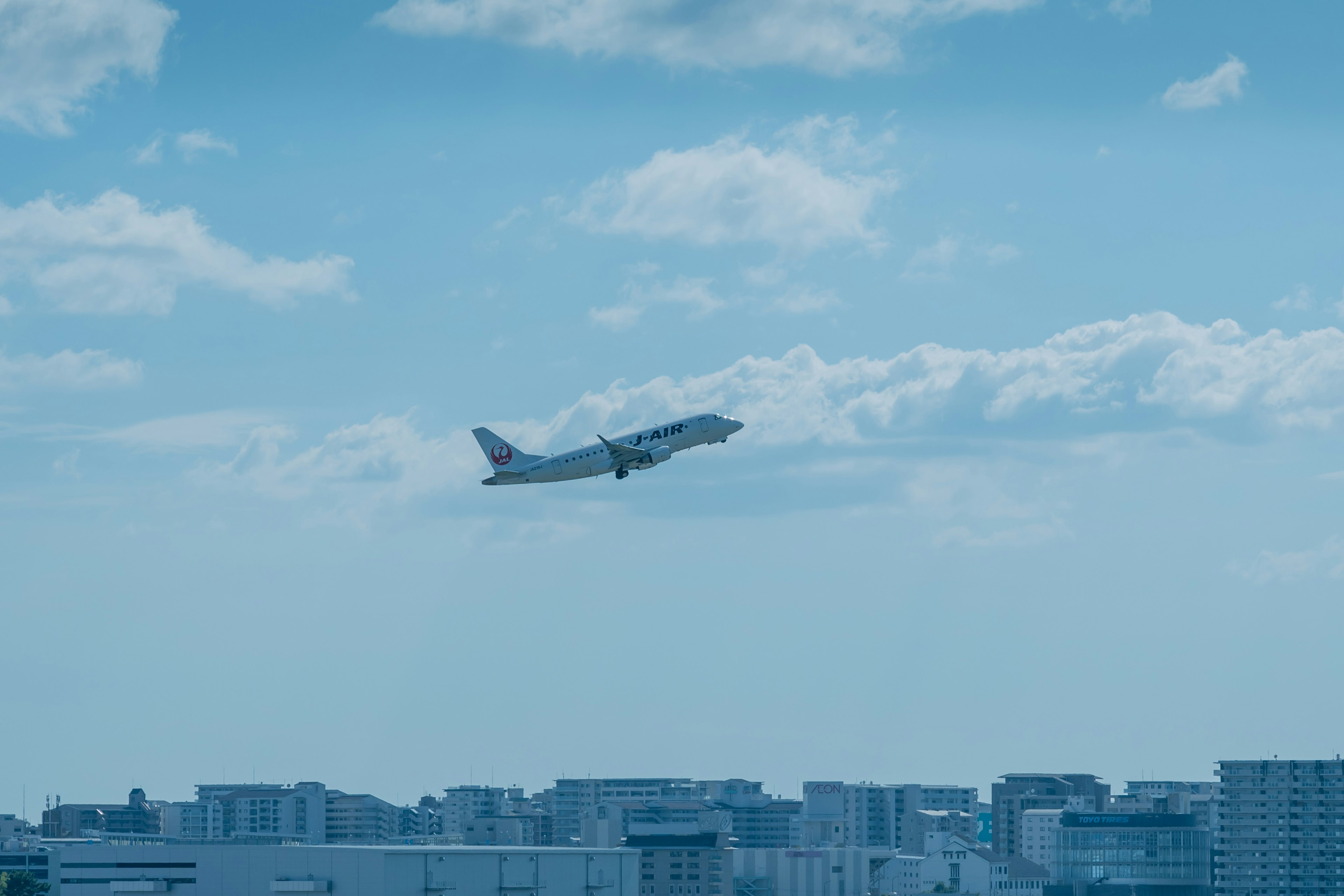 Aereo che decolla contro un cielo blu e lo skyline urbano