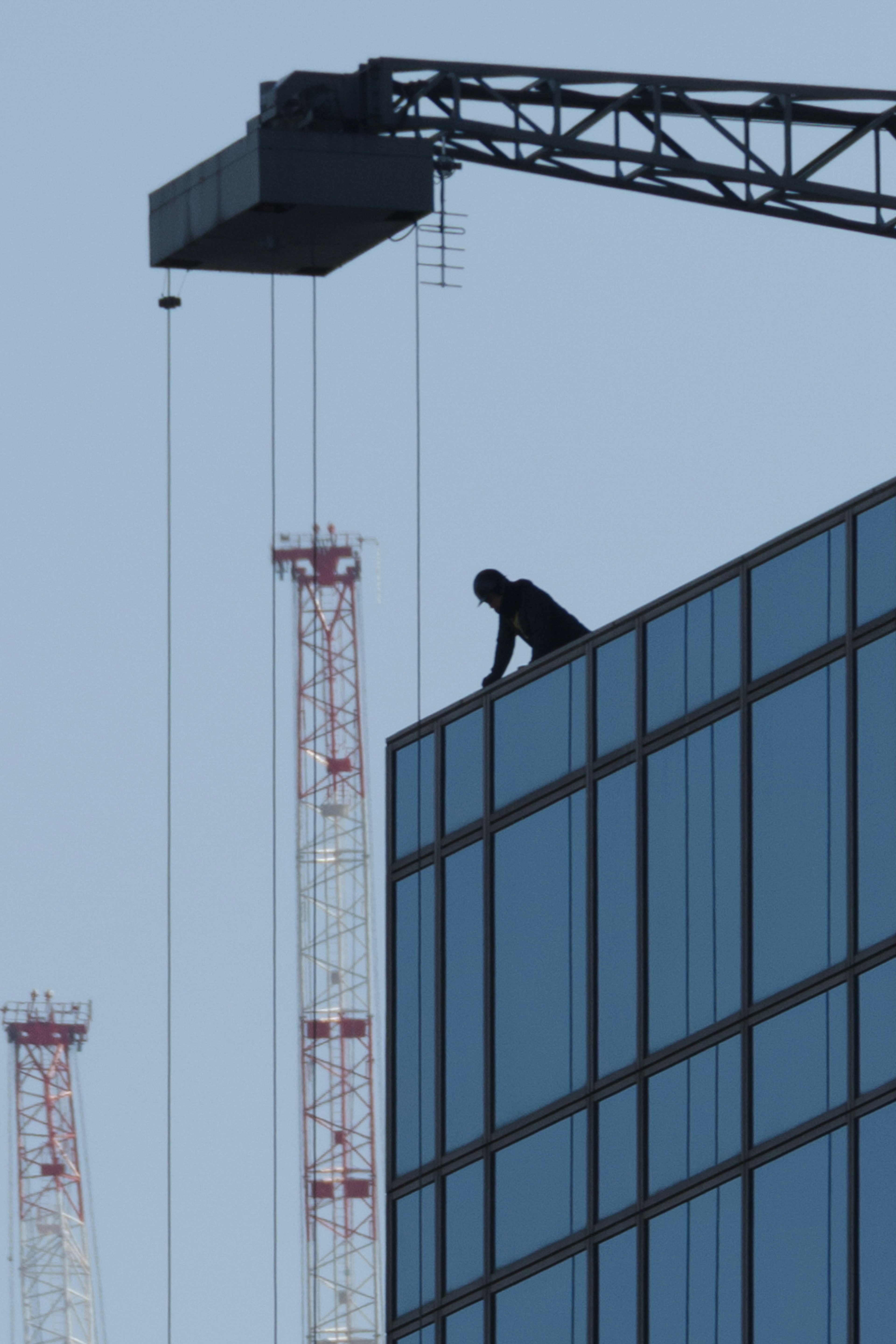 Siluet pekerja konstruksi di atap gedung pencakar langit