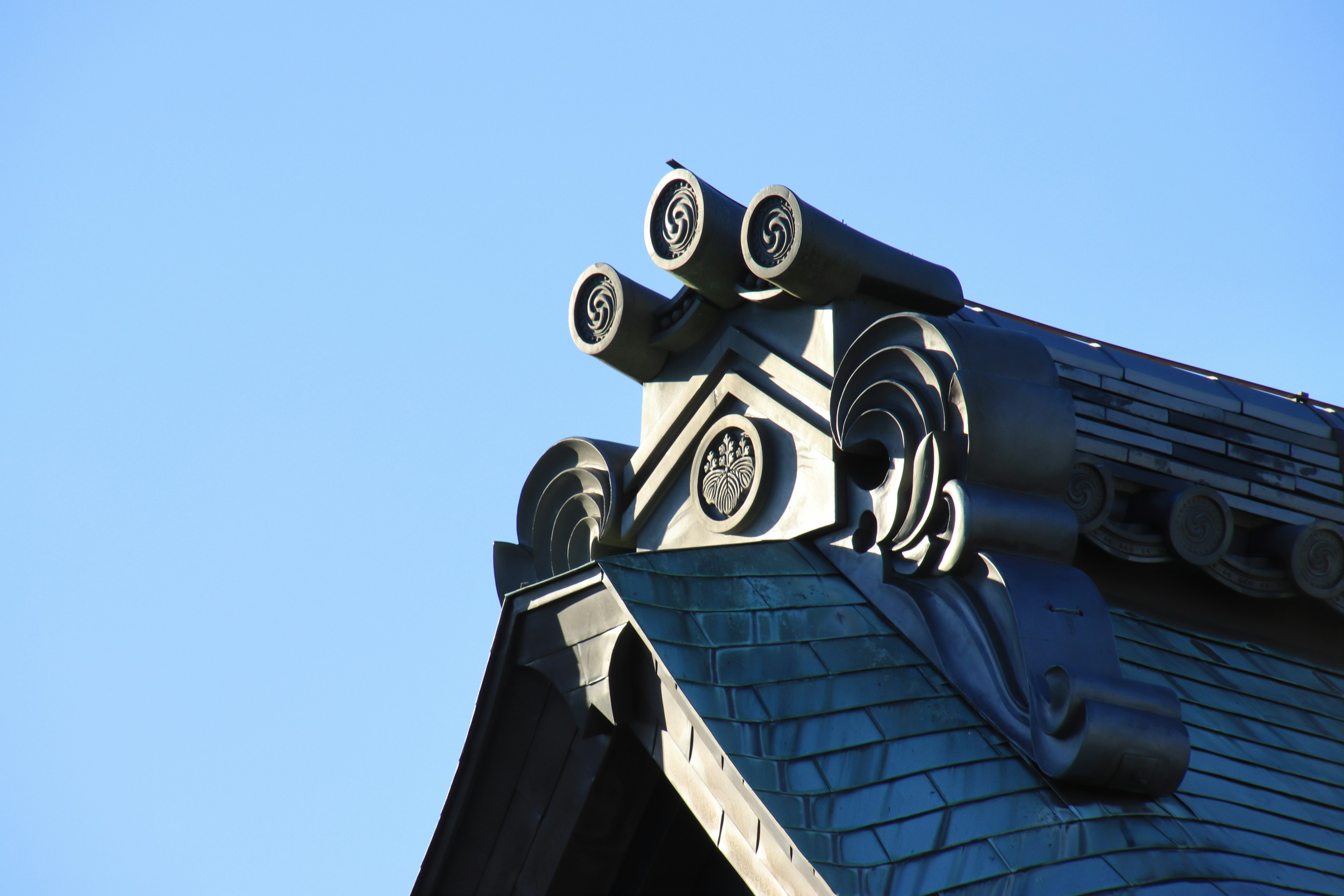 Decorative design of a traditional Japanese roof apex against a blue sky