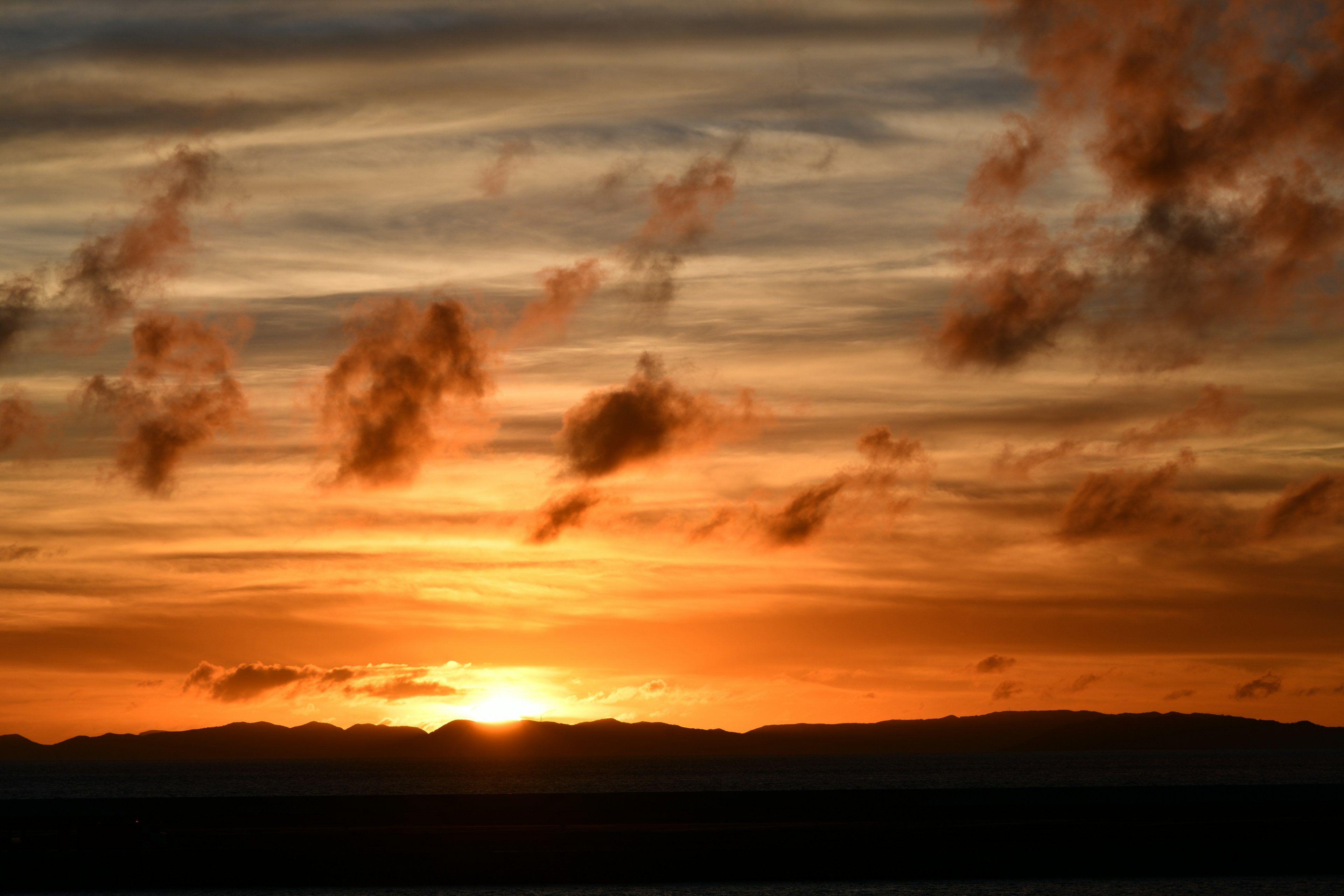 Bellissimo paesaggio al tramonto con cielo arancione e giallo e montagne lontane