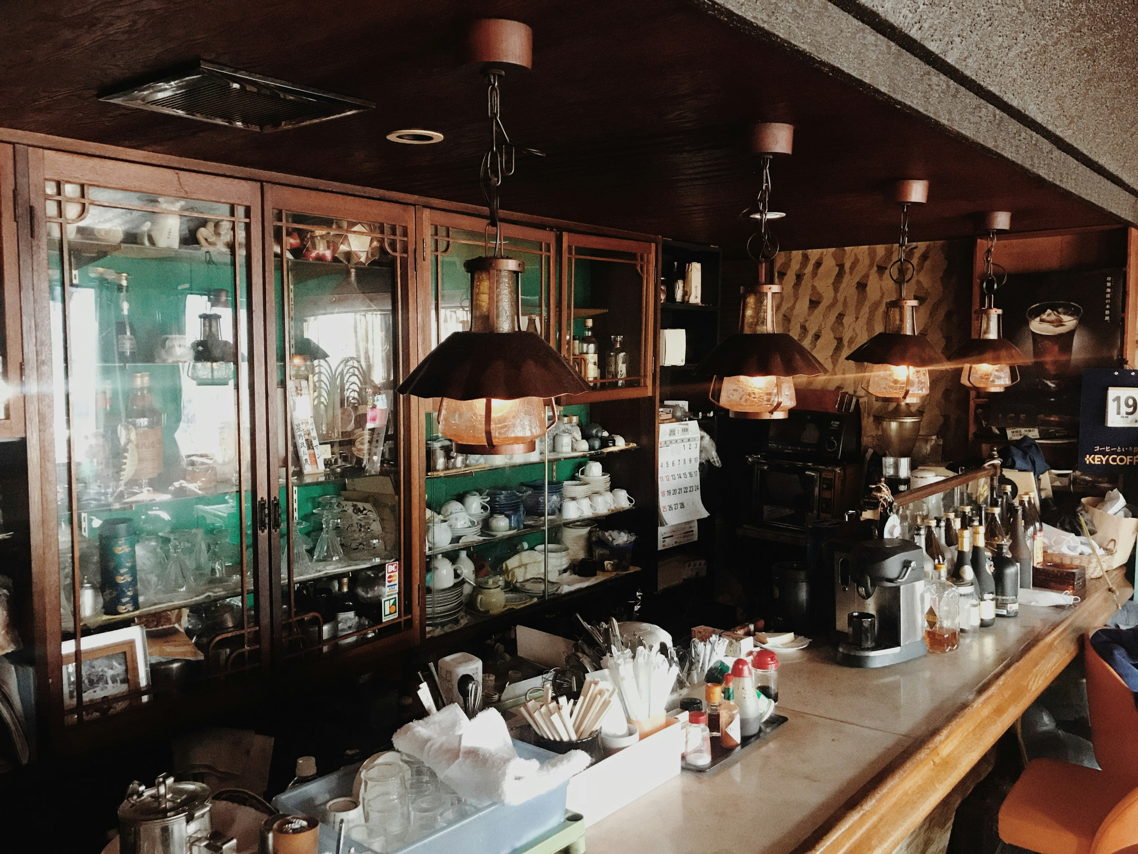 Interior de una cafetería con un mostrador de café y lámparas decorativas