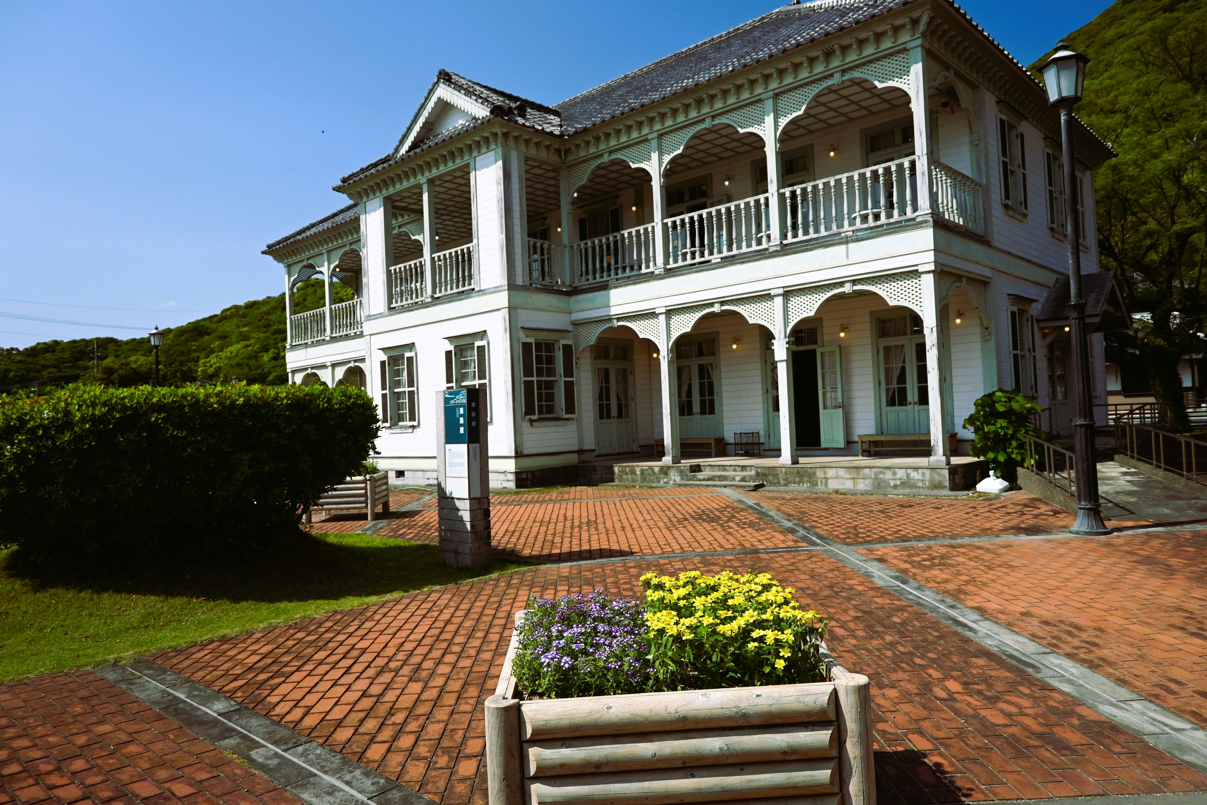 Beautiful Western-style building with white exterior surrounded by greenery and brick pathway