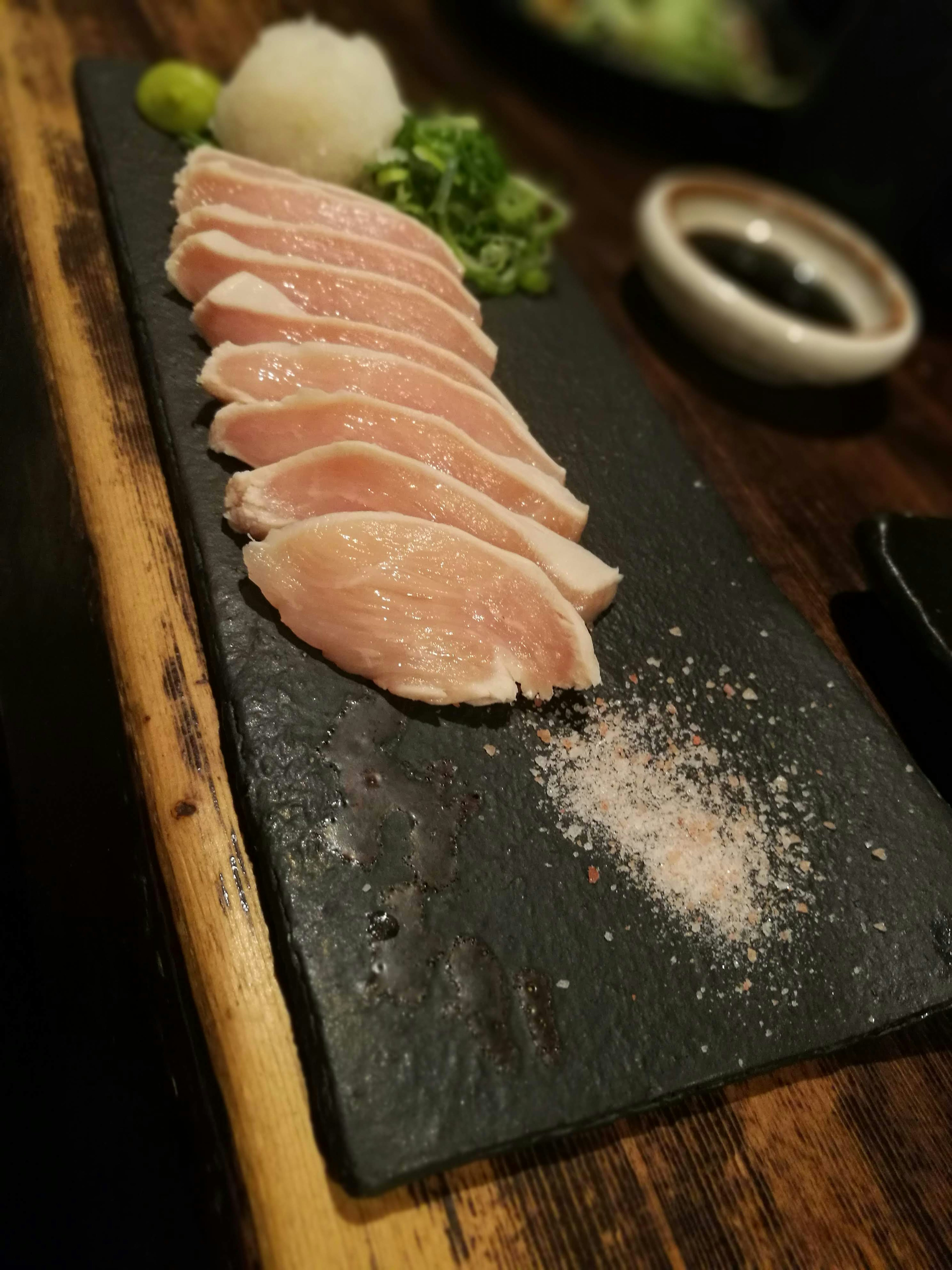 Sliced duck meat arranged on a black stone plate