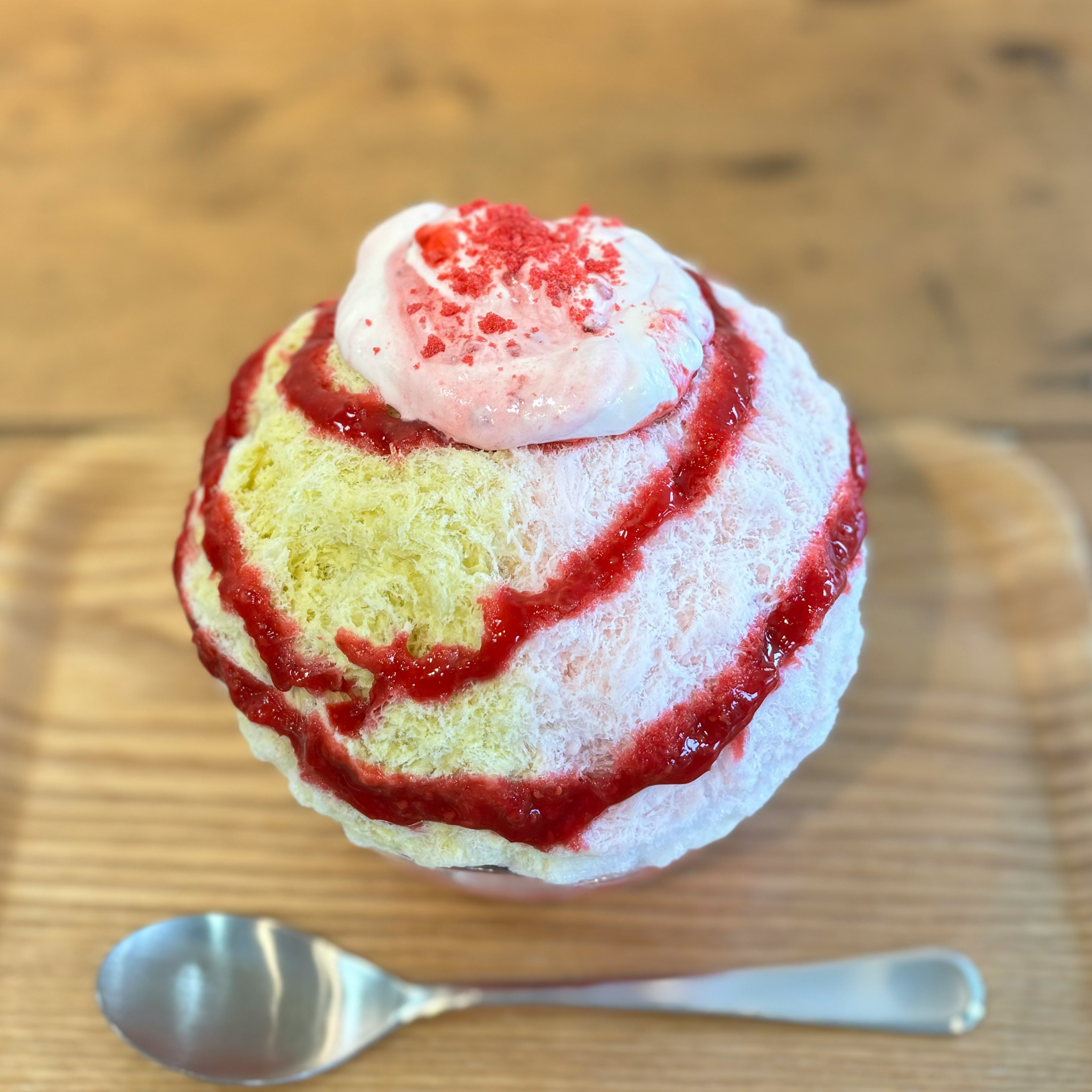 A serving of shaved ice topped with strawberry sauce and cream