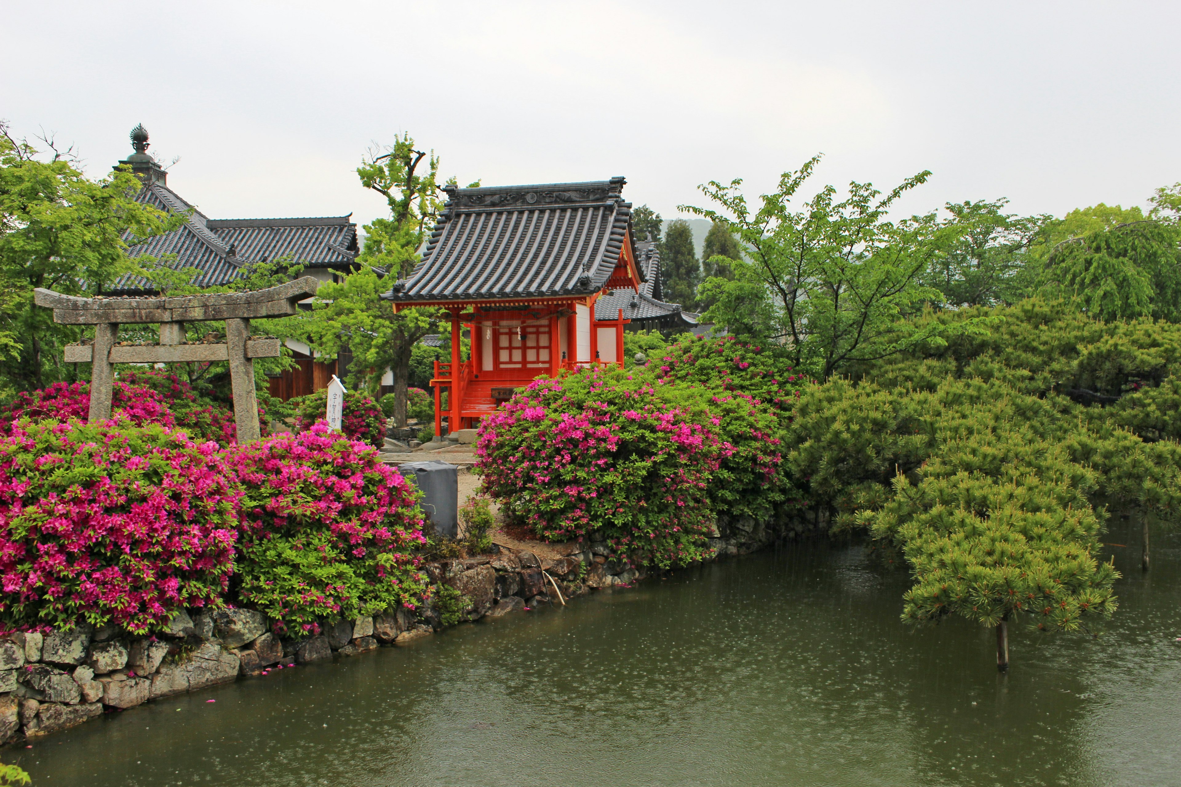 A beautiful Japanese garden featuring a red building and vibrant flowers