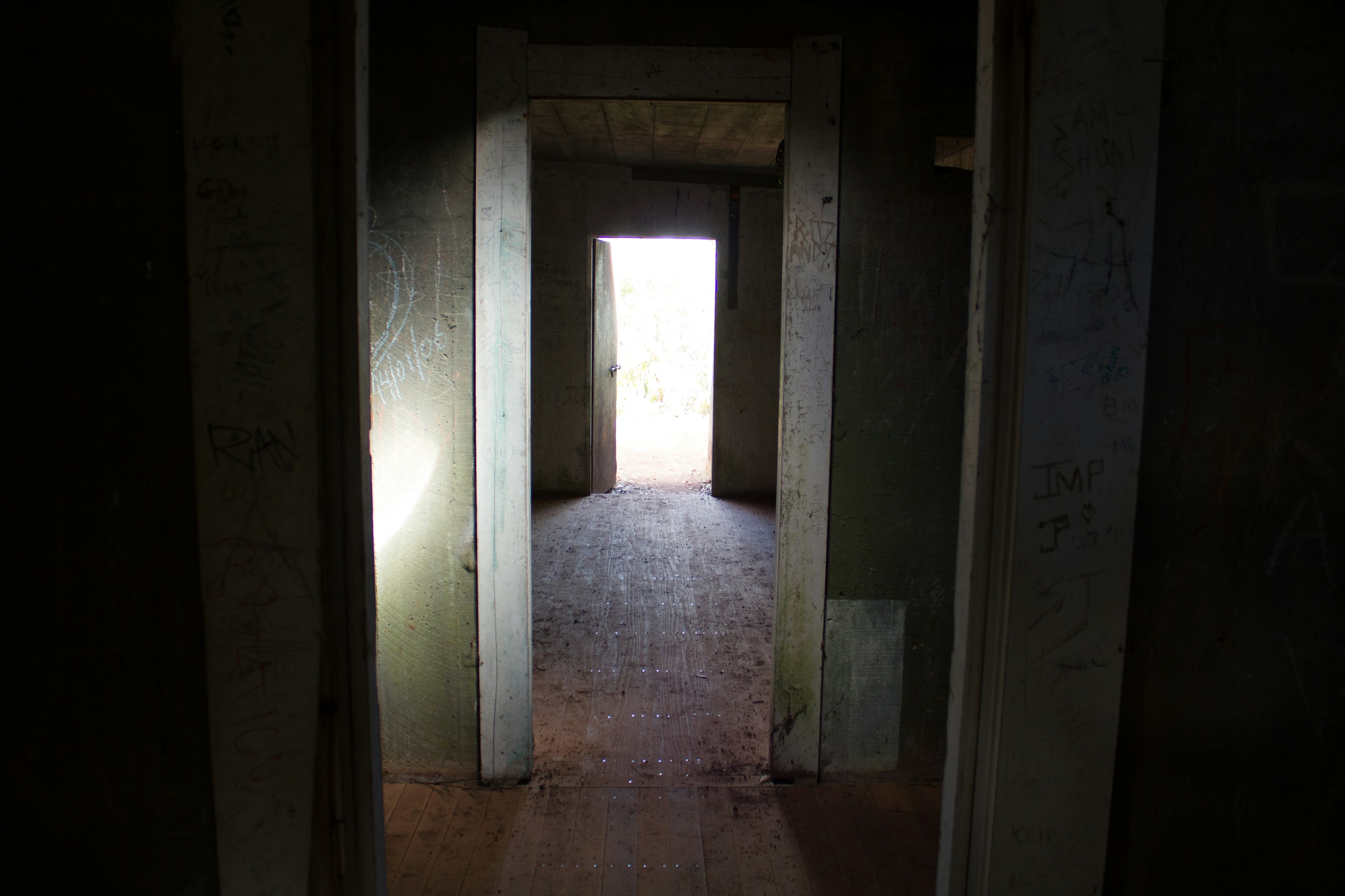 Interior of an old building with a dark hallway leading to a bright light