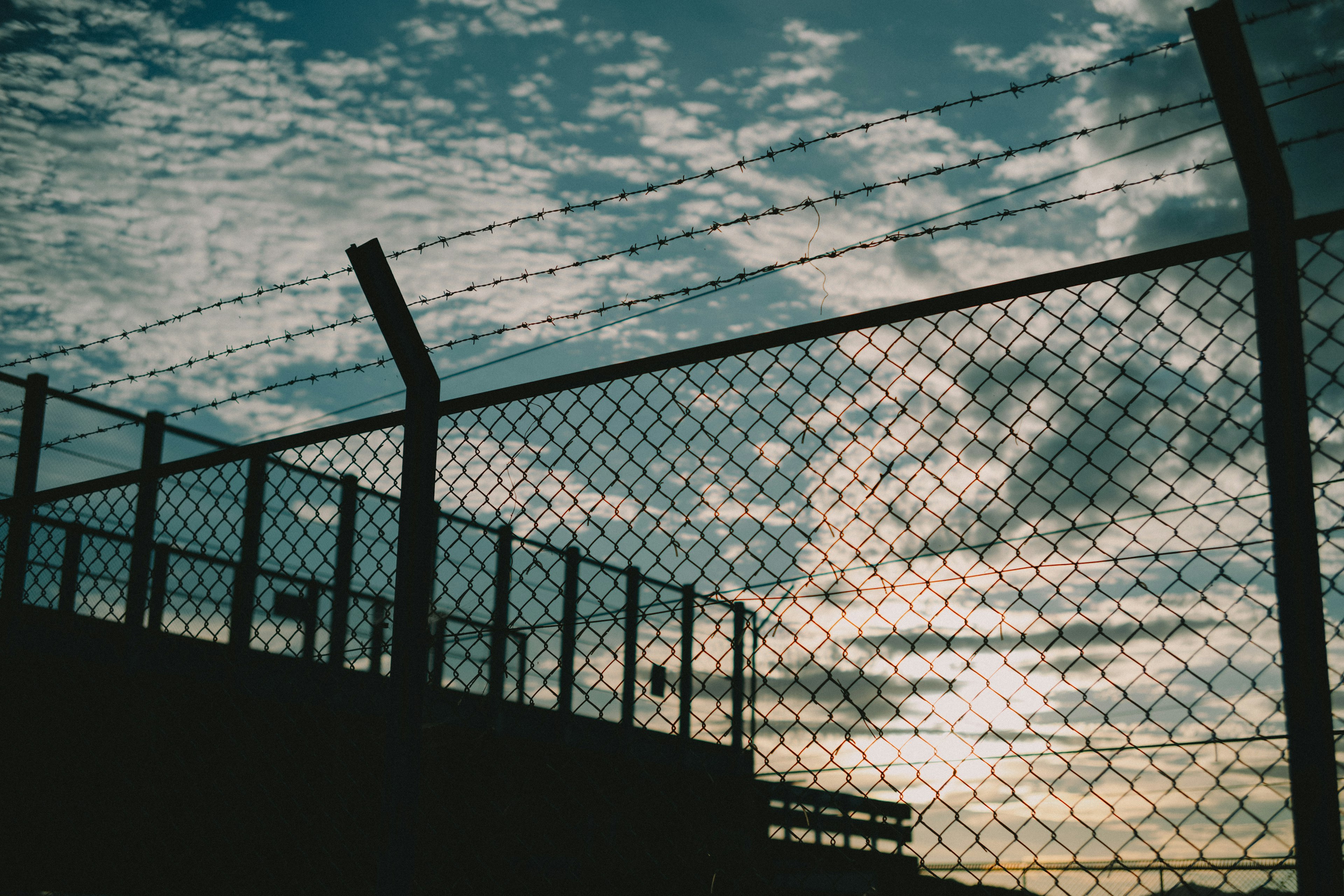 Silhouette of a fence against a sunset sky