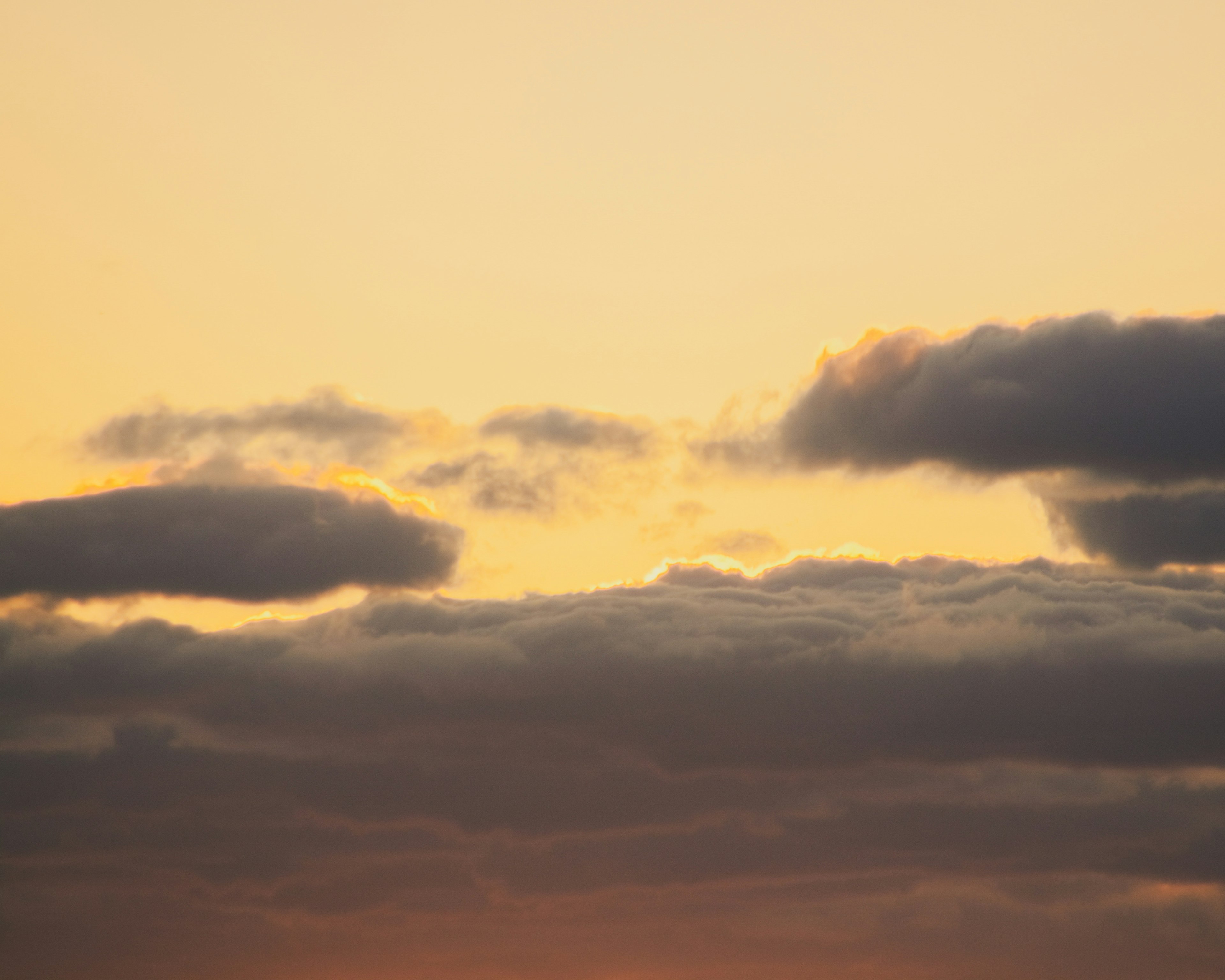 Clouds in a soft orange sky at sunset