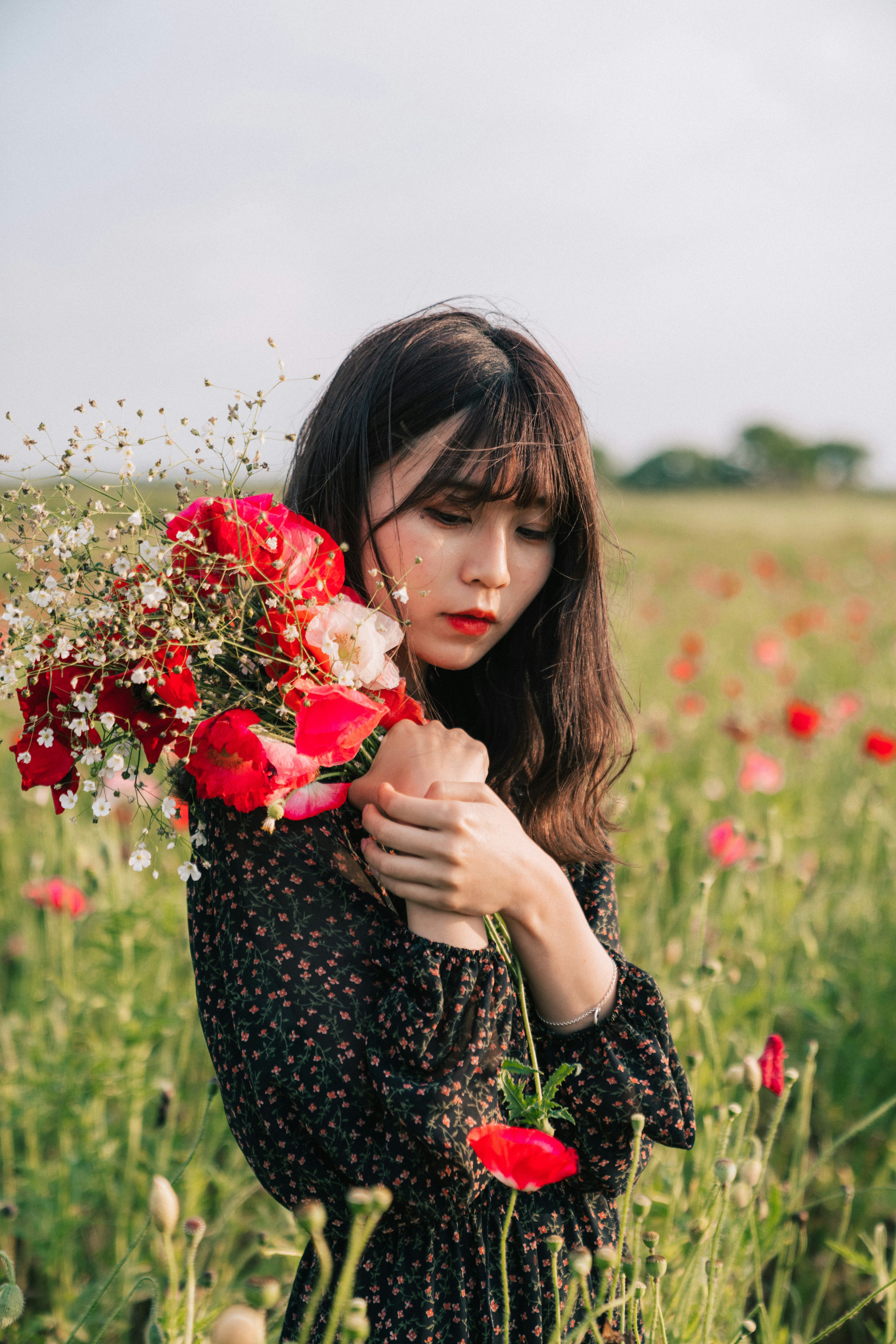 Una hermosa mujer sosteniendo un ramo de flores rojas en un campo