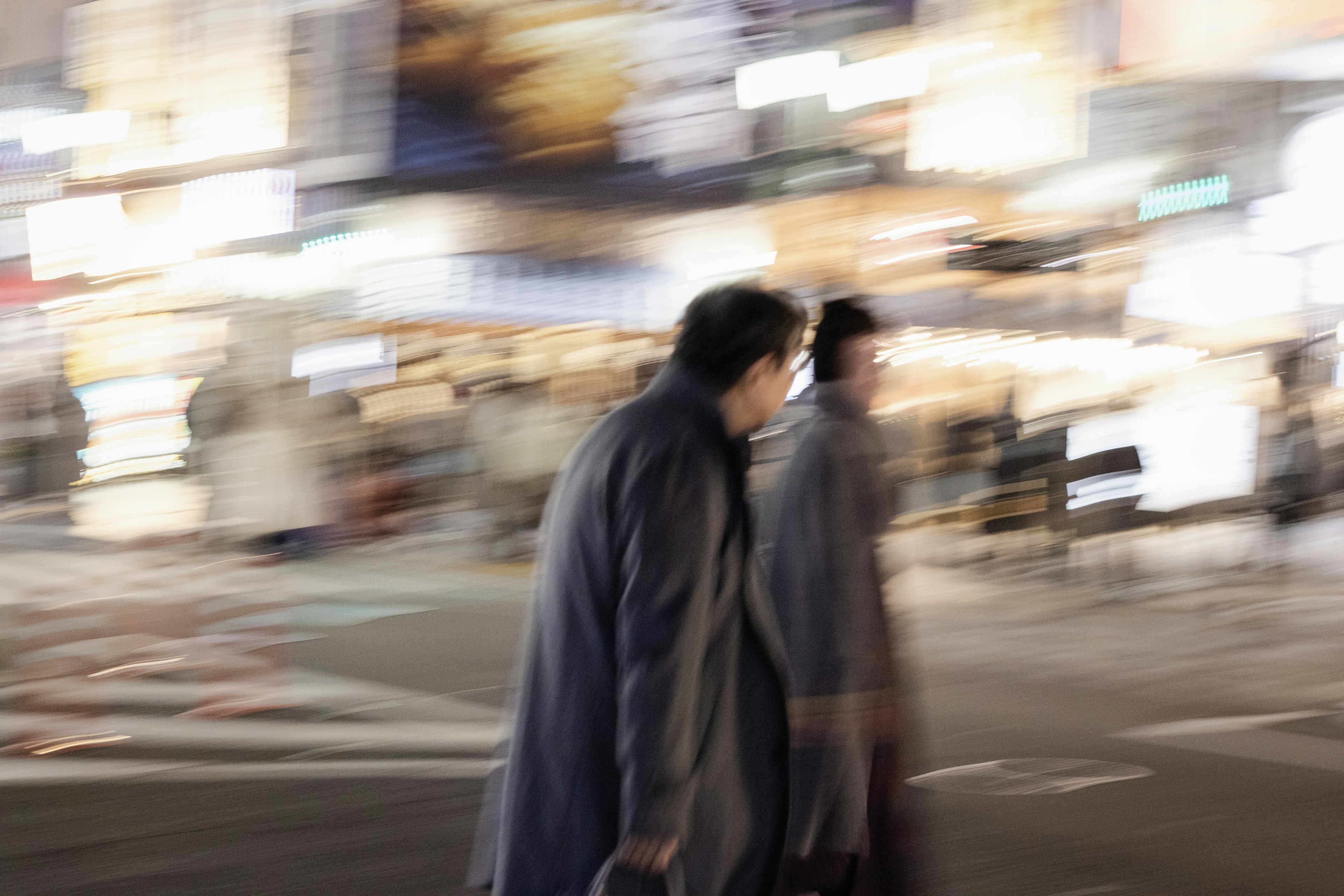 Silhouettes de deux personnes traversant une rue avec un arrière-plan flou