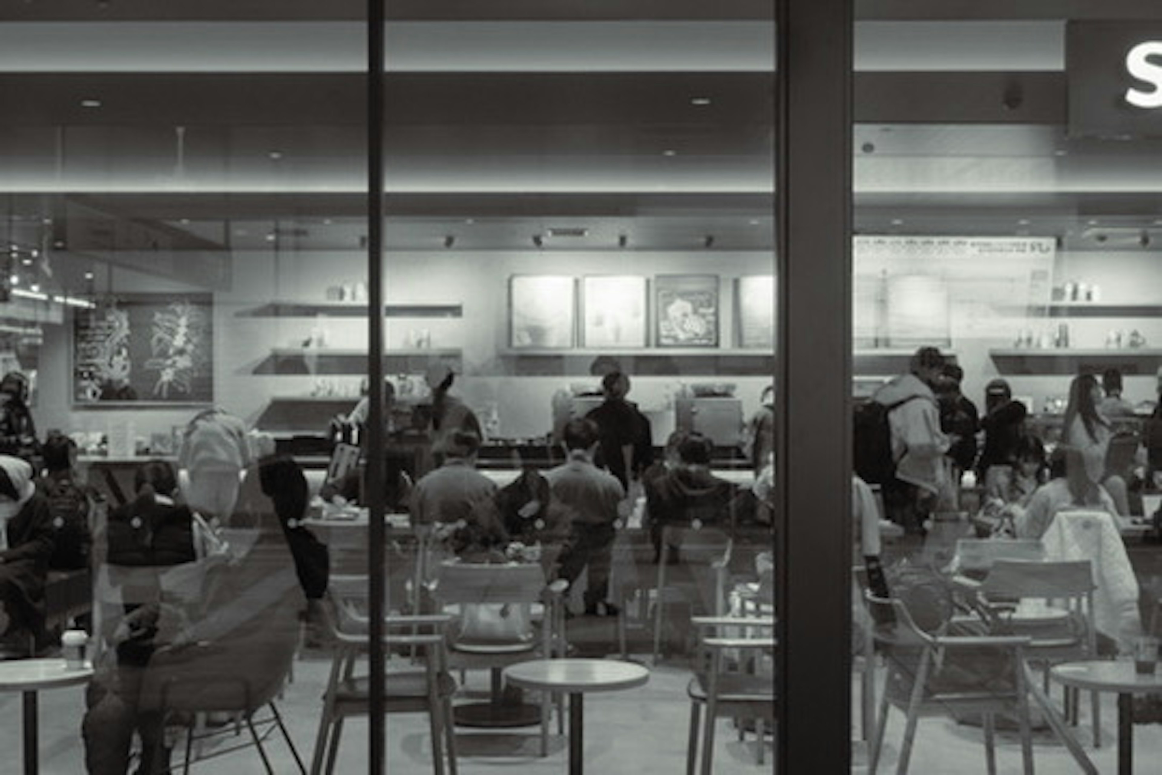 View of a café with people and tables seen through a window