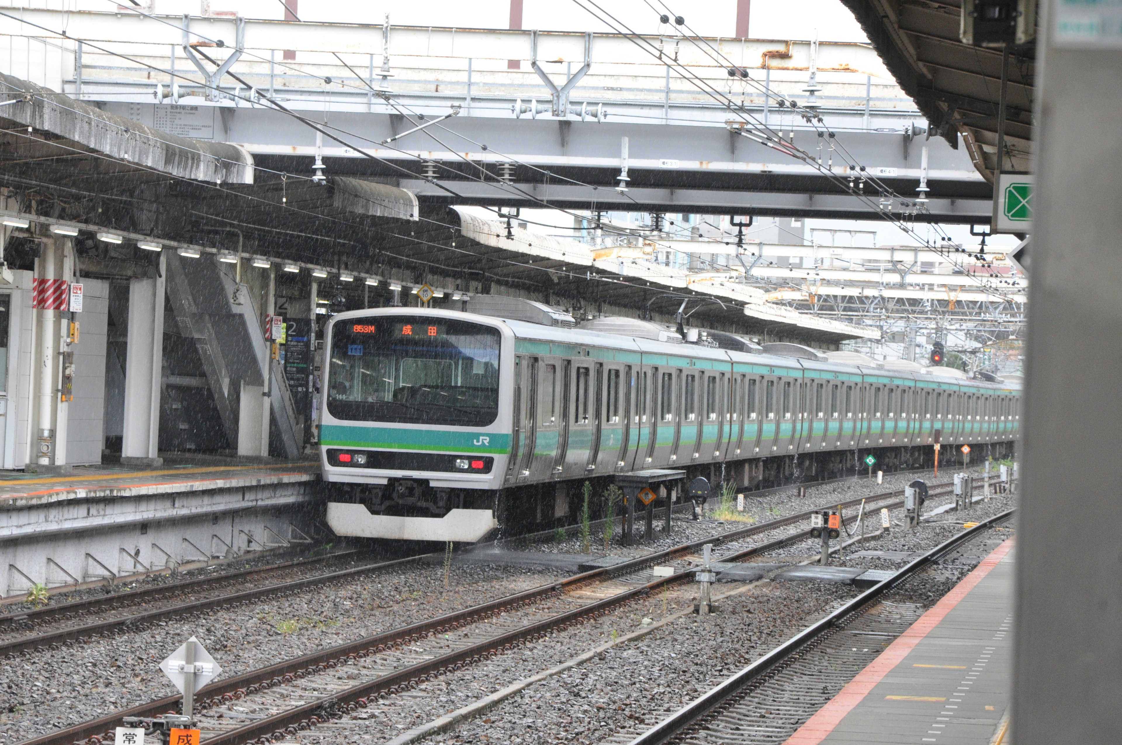 Sebuah kereta hijau tiba di stasiun dengan beberapa jalur