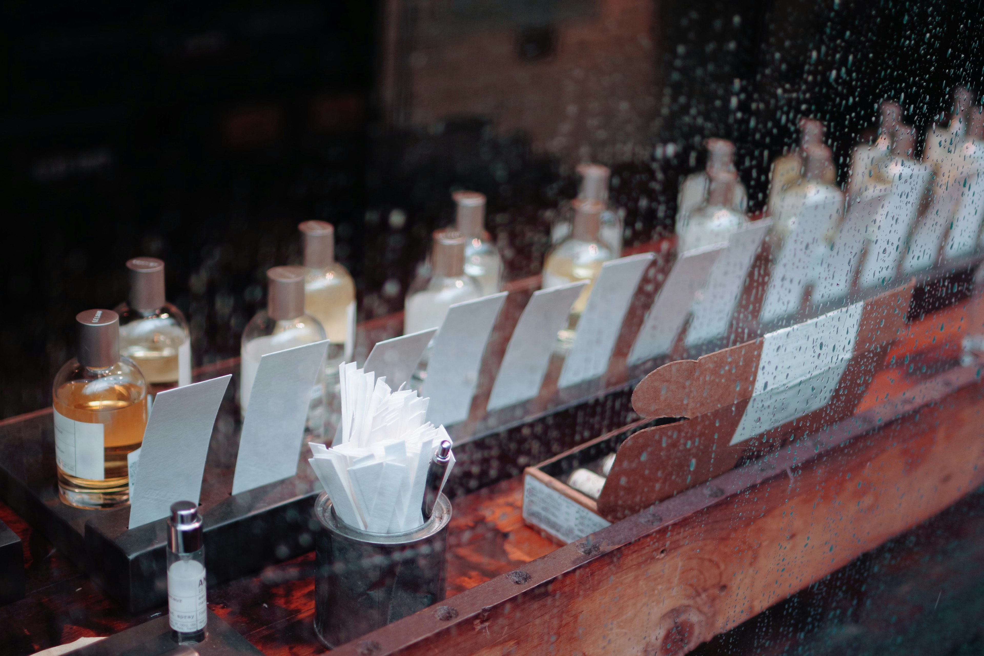 Vue de bouteilles de parfum alignées dans un magasin à travers du verre mouillé par la pluie