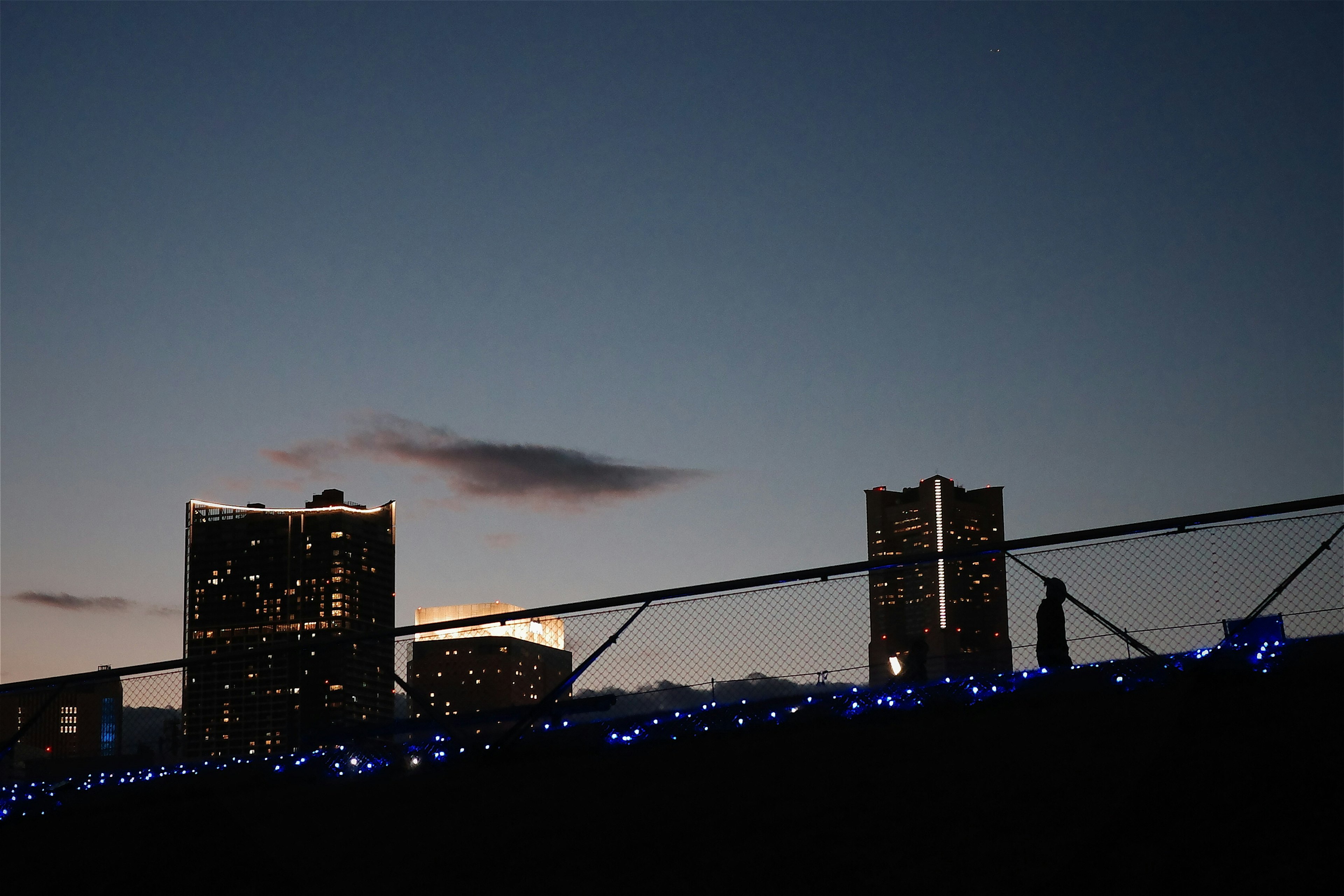 黄昏天空下的建筑轮廓与蓝色灯光