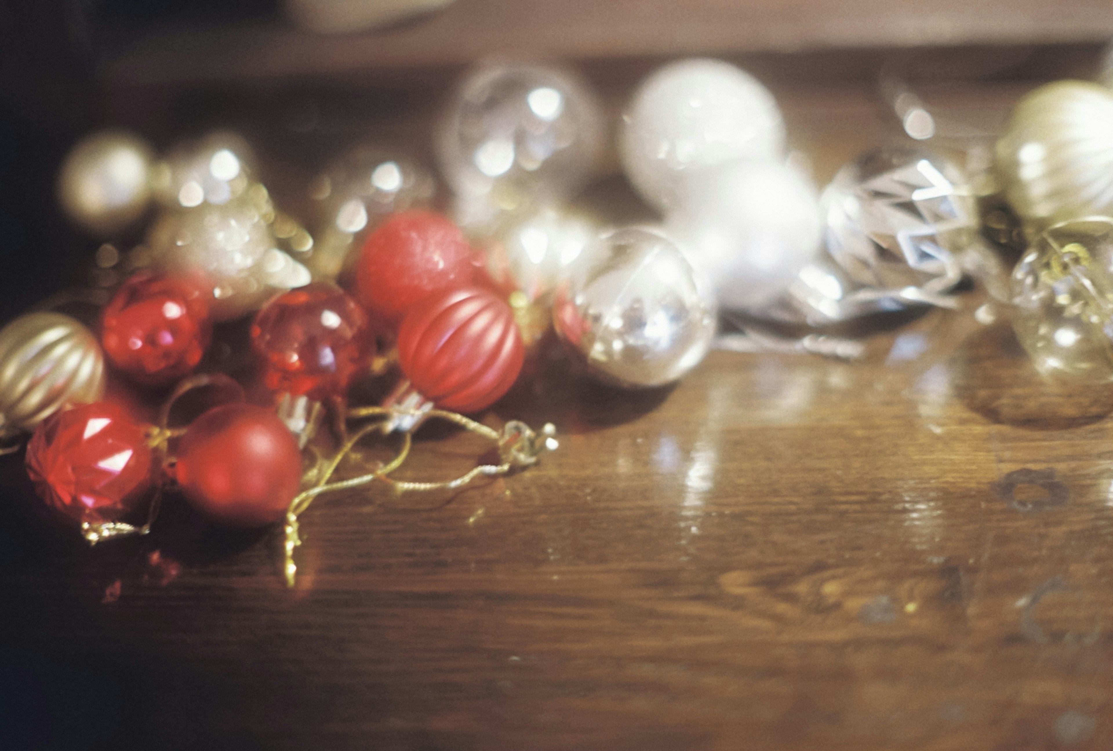 Red white and gold Christmas ornaments scattered on a wooden table