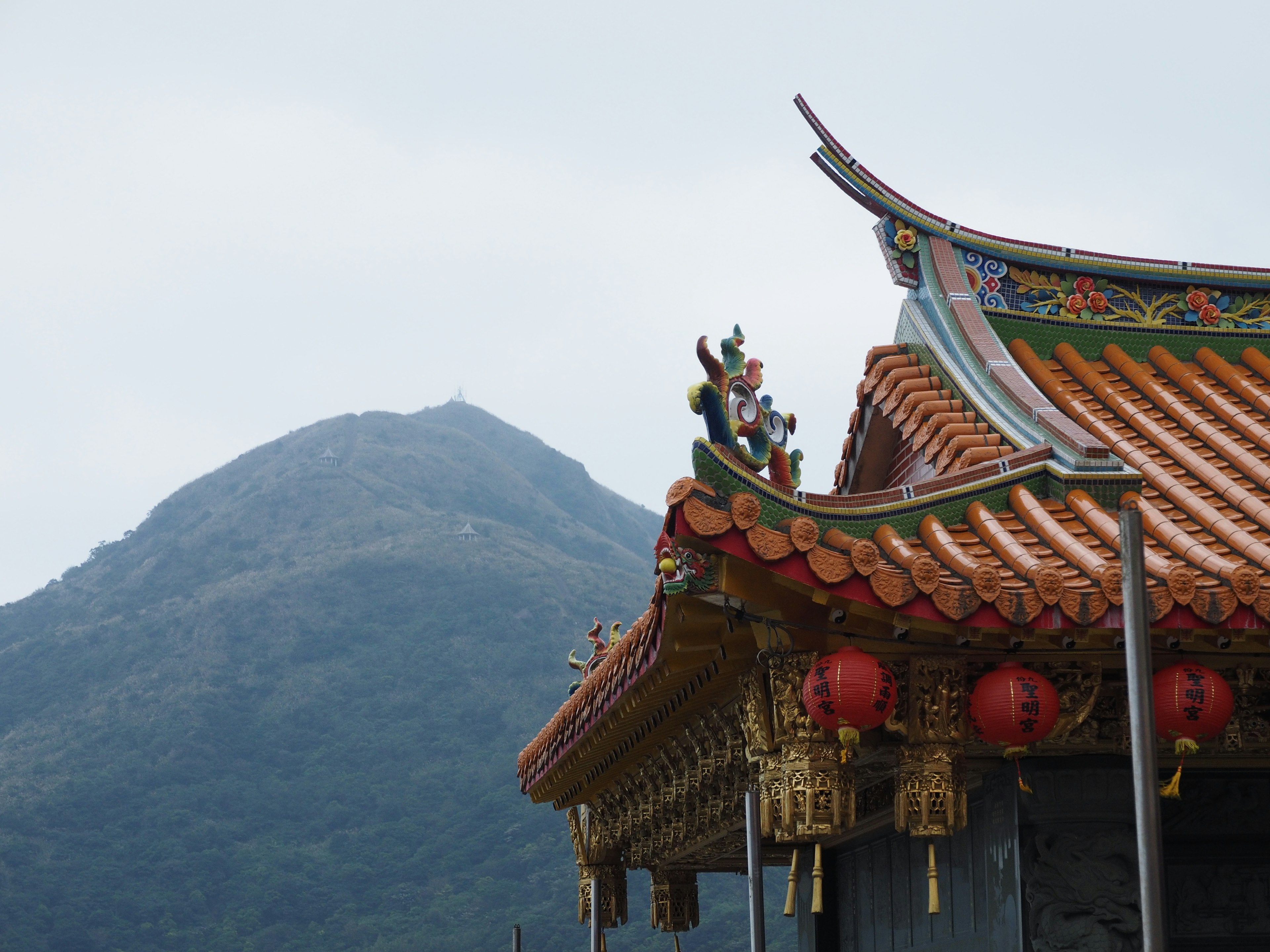 Scenic view of a decorative roof with lanterns and a mountain backdrop