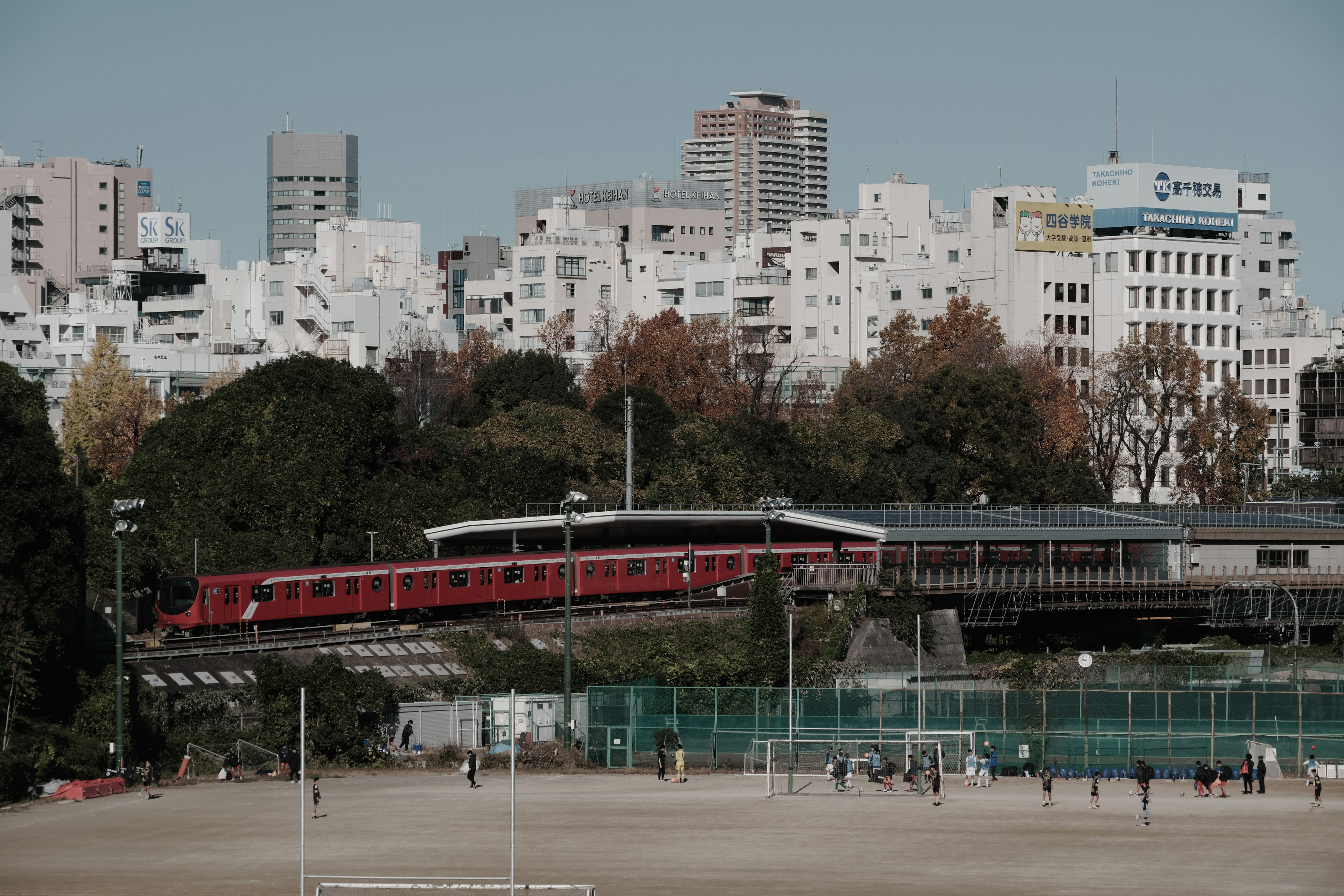 Red train running on an elevated track with city background