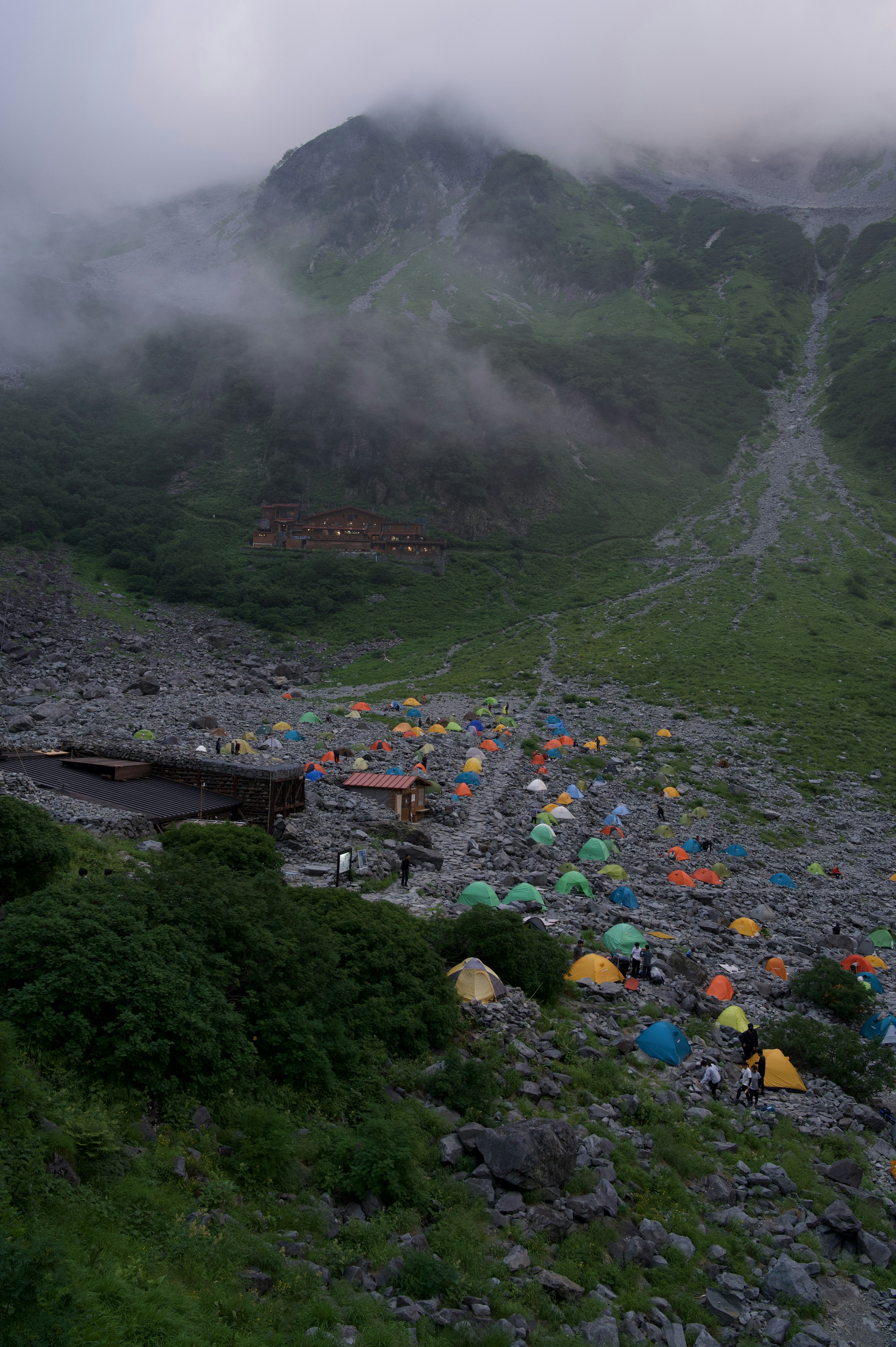 Colorful tents in a camp site surrounded by misty mountains