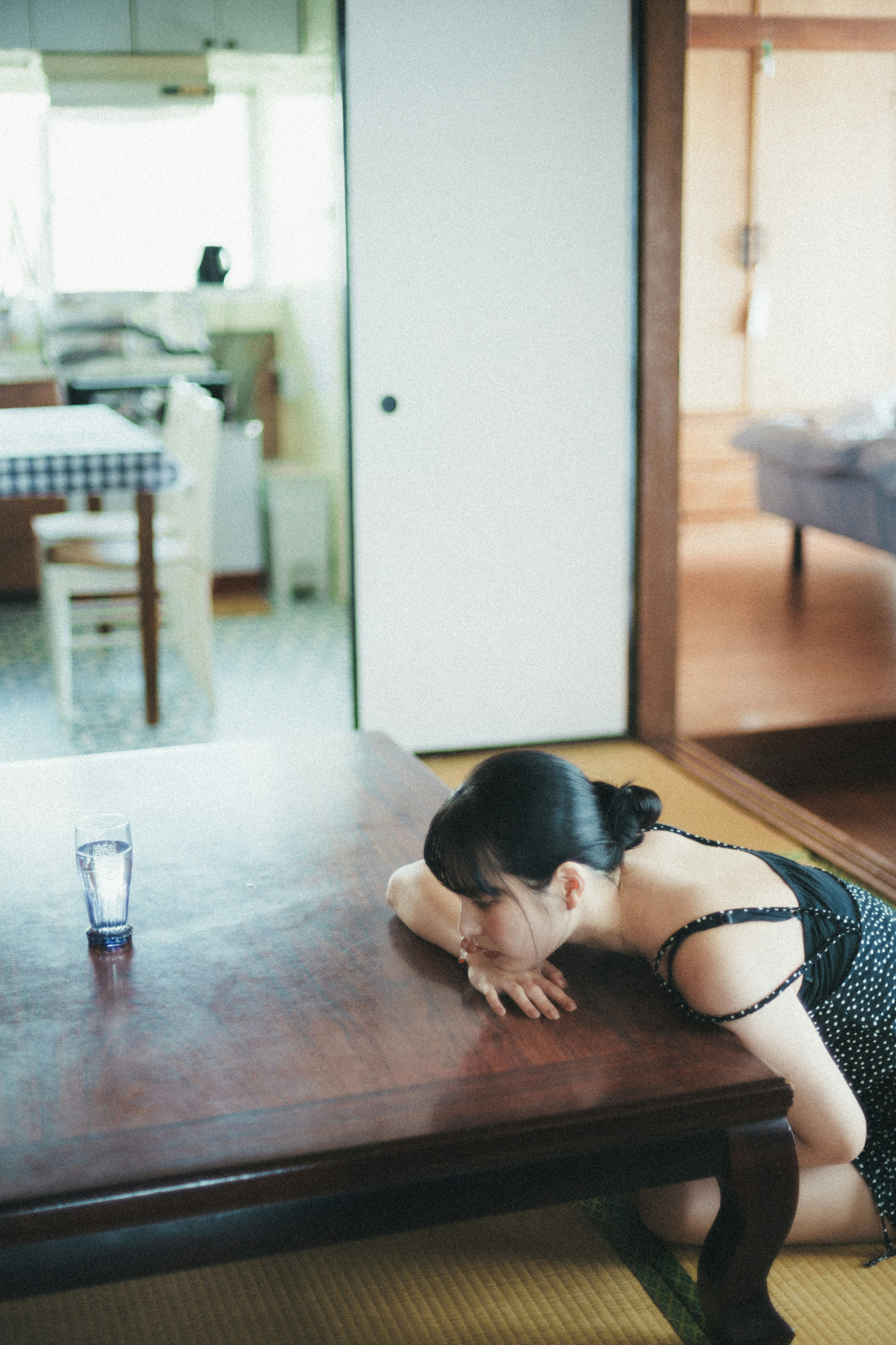 A woman resting on a wooden table with a kitchen in the background