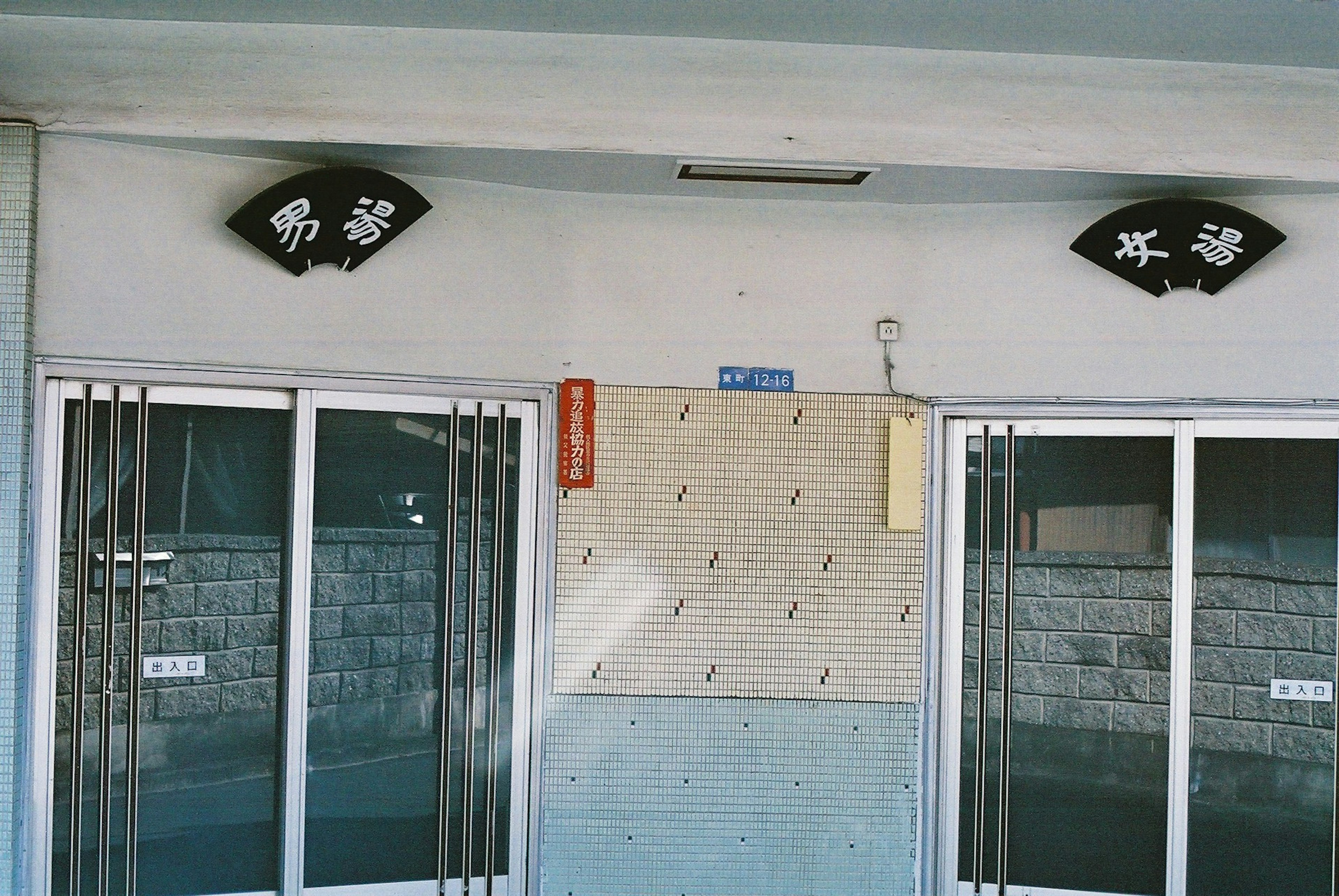 Entrance of a building featuring two signs and glass doors