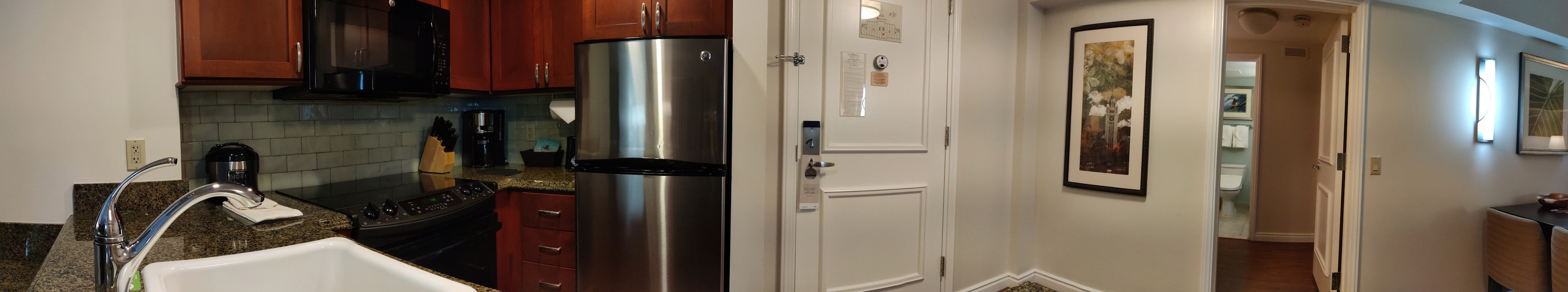 Panoramic view of kitchen and hallway featuring modern design stainless steel refrigerator and wooden cabinets