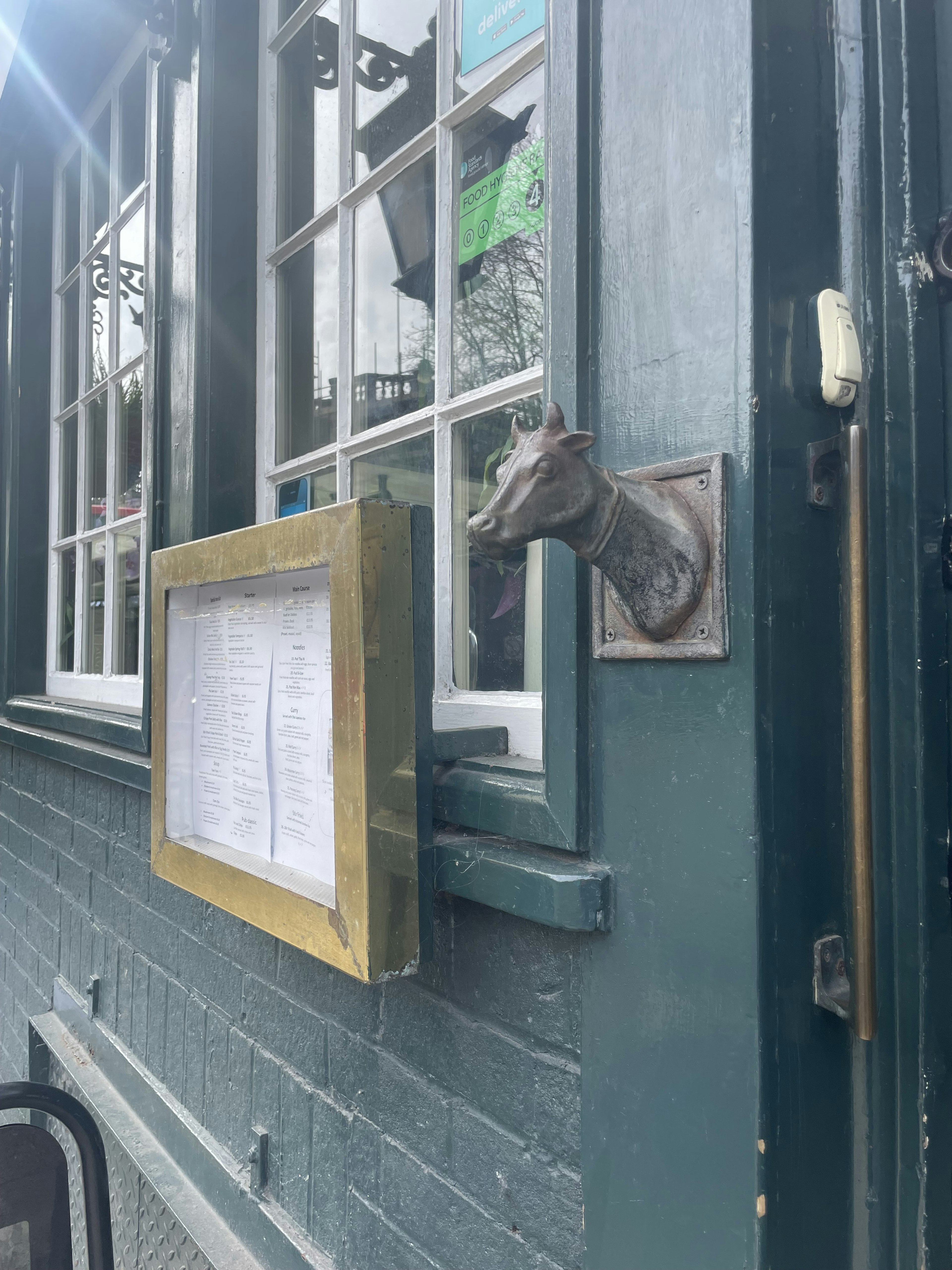 Metal dog head door handle next to a menu frame at a window