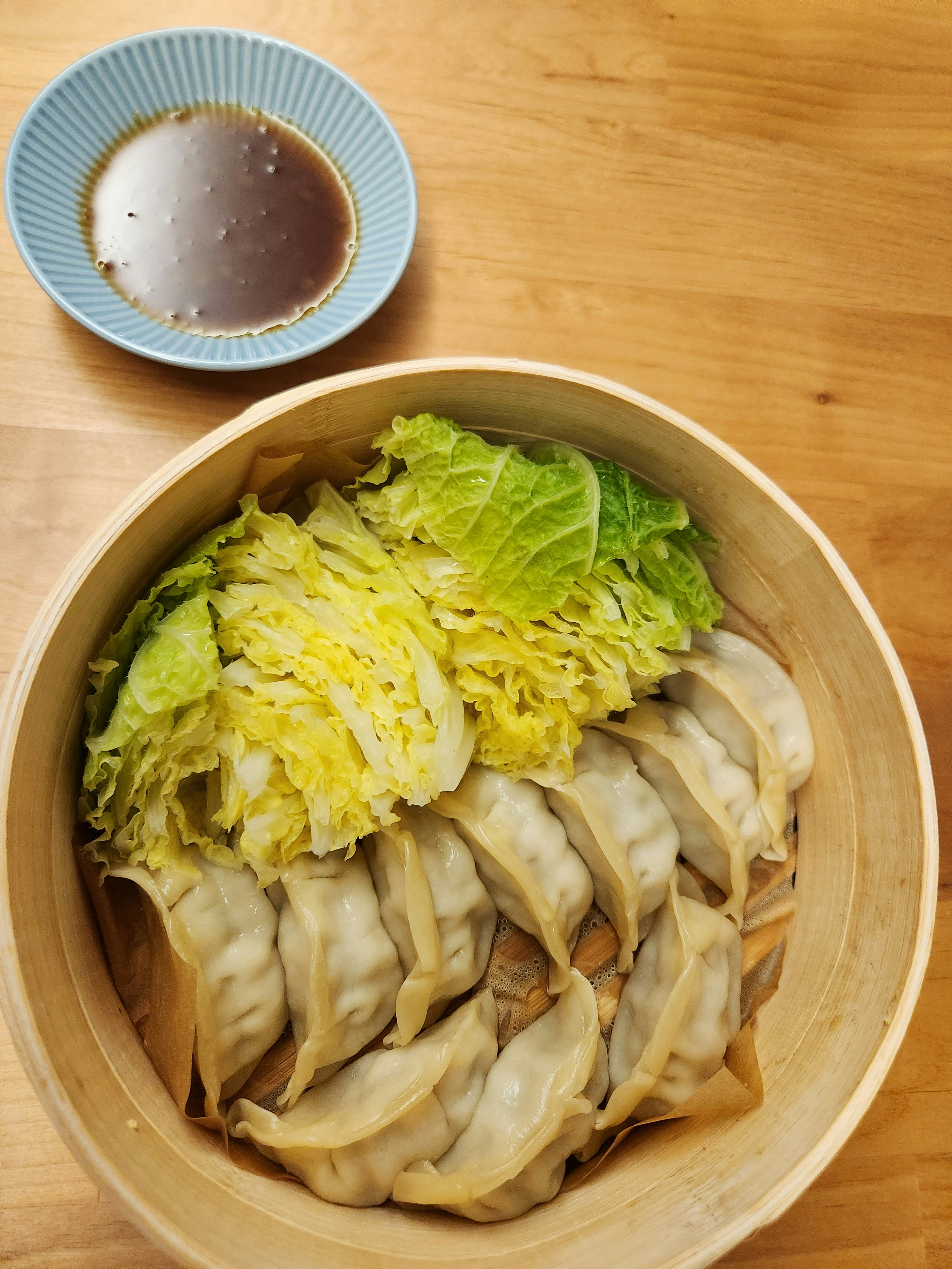 Steamed dumplings arranged with lettuce in a bamboo steamer