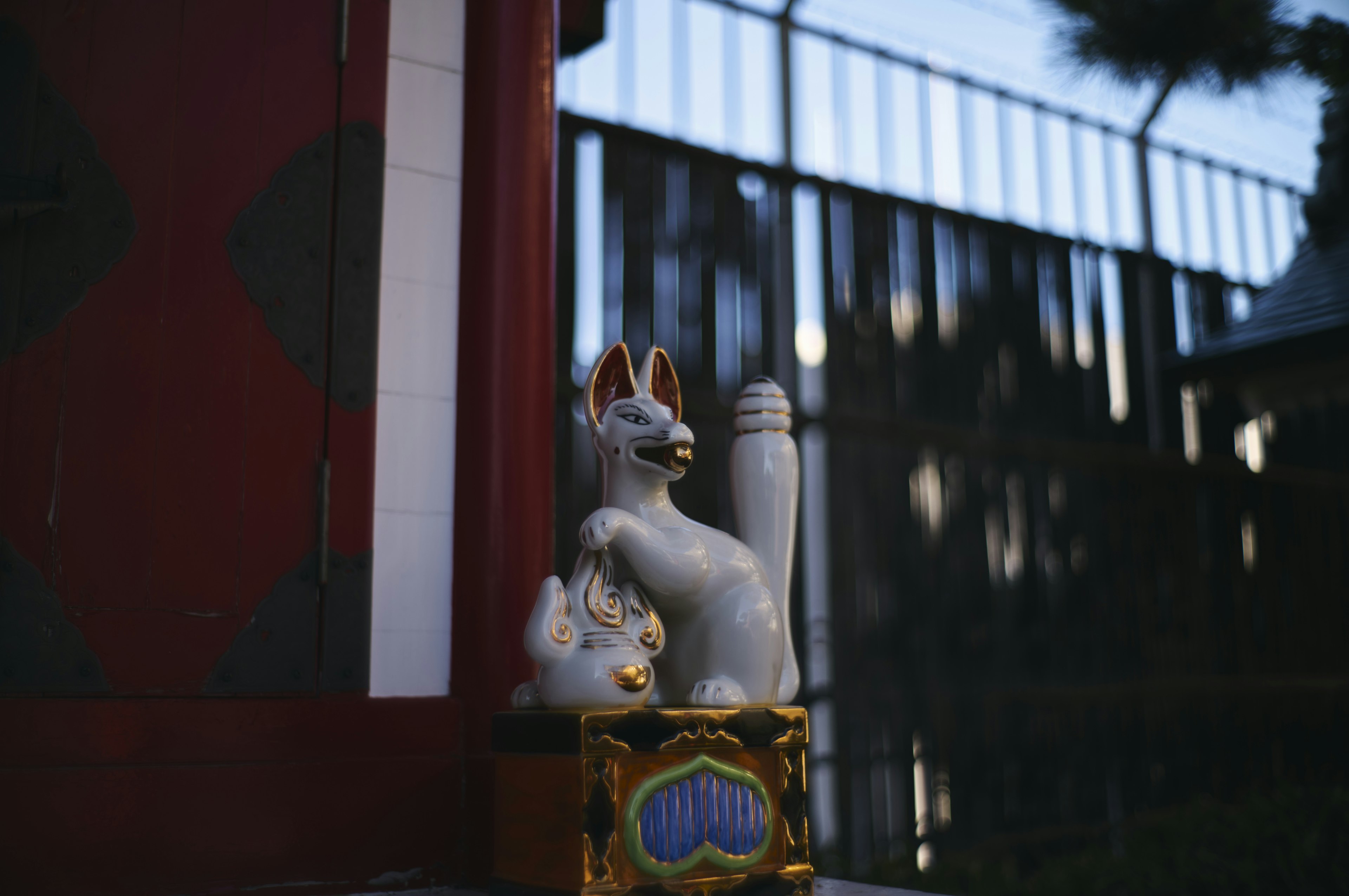 Una estatua de zorro blanco sobre un pedestal dorado en un jardín