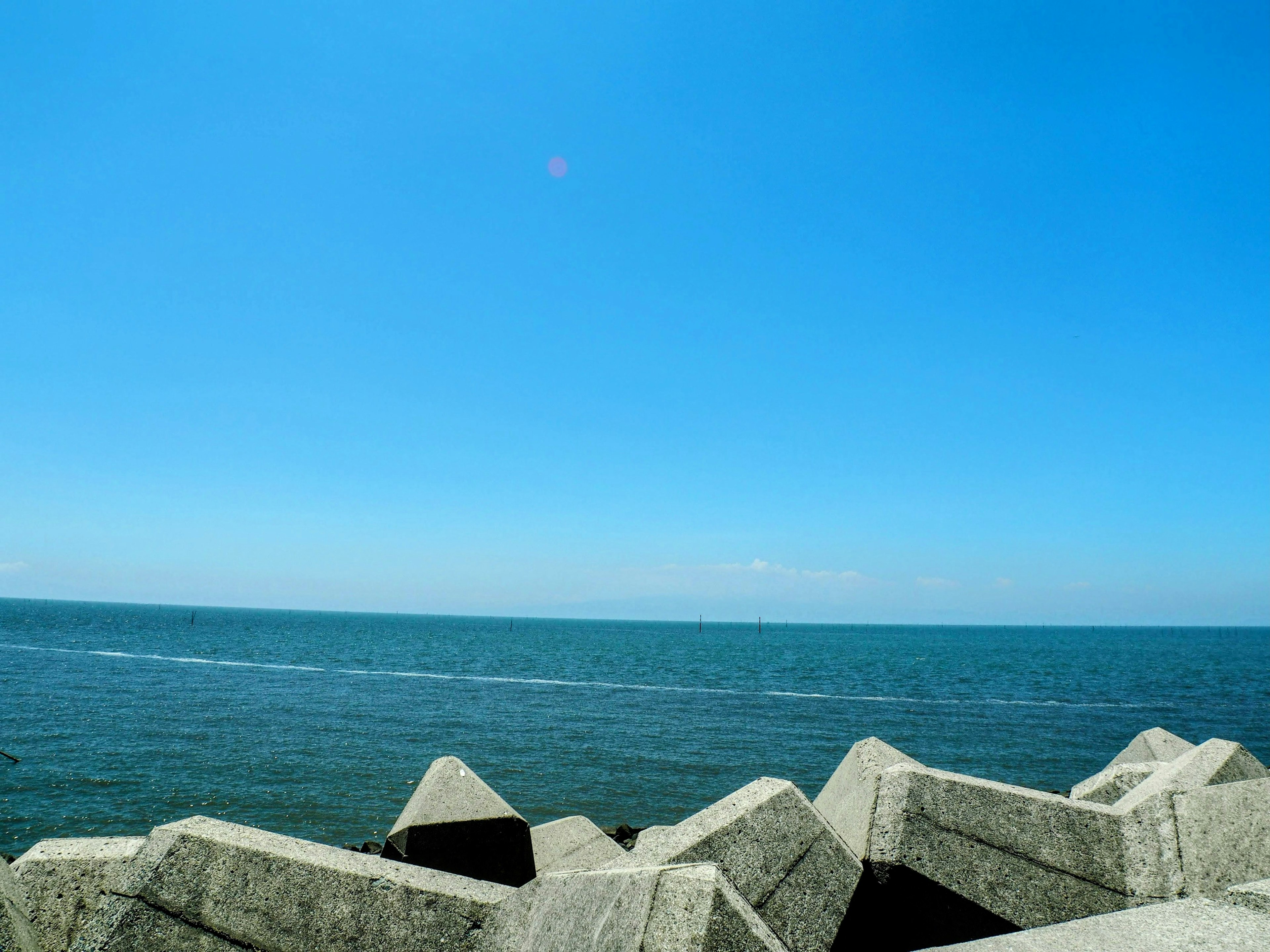 Rompeolas de concreto con cielo azul y océano al fondo