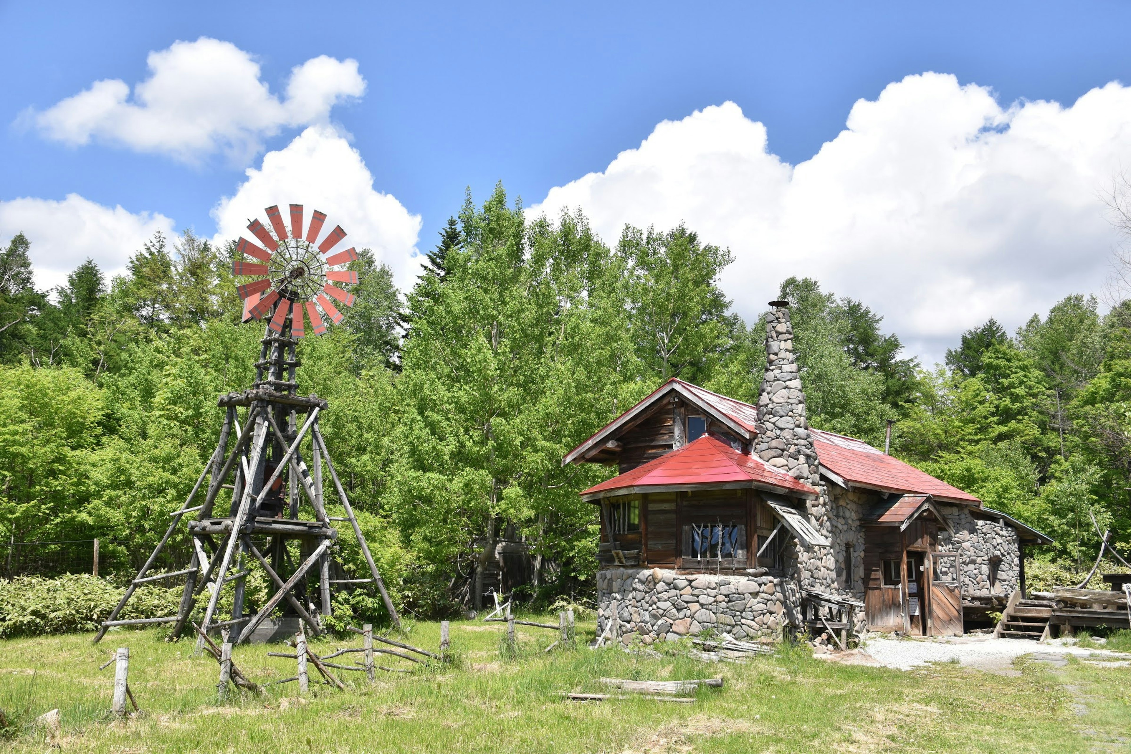 A picturesque rural scene featuring a windmill and a stone house