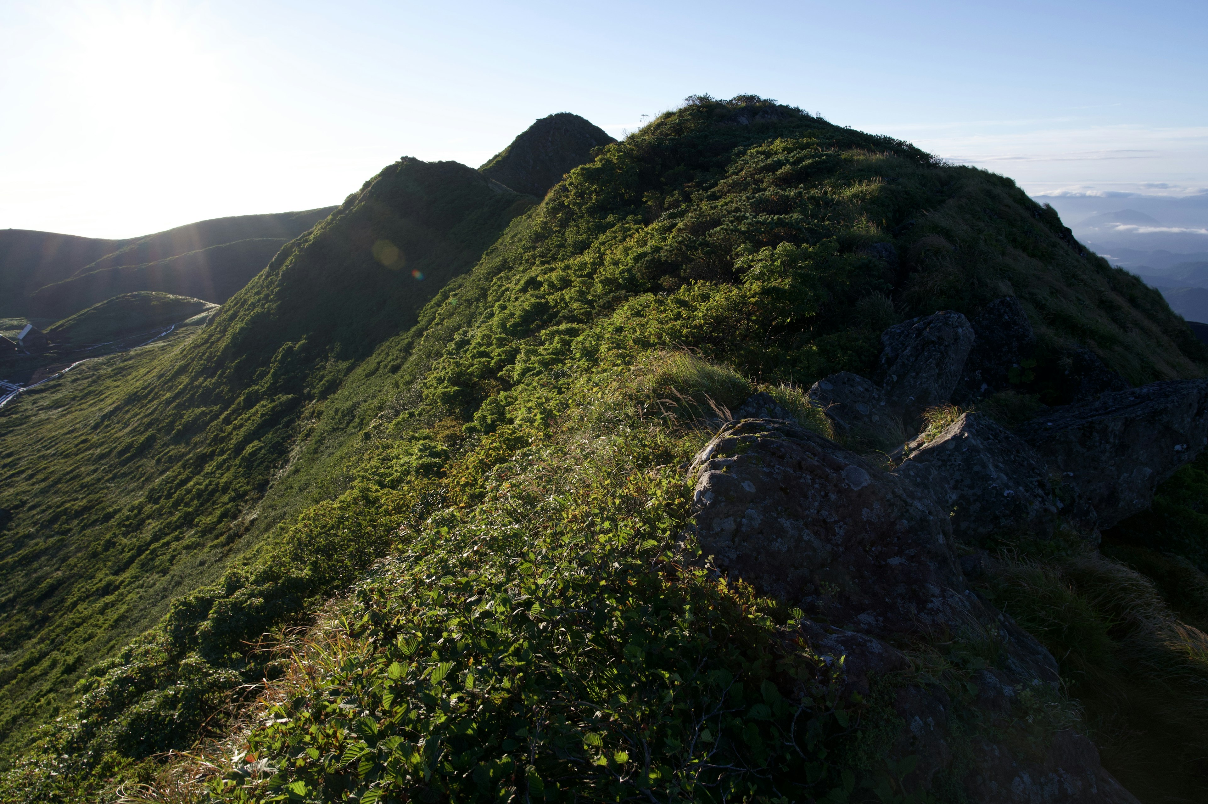 緑に覆われた丘陵の風景と日差しの中の山の稜線