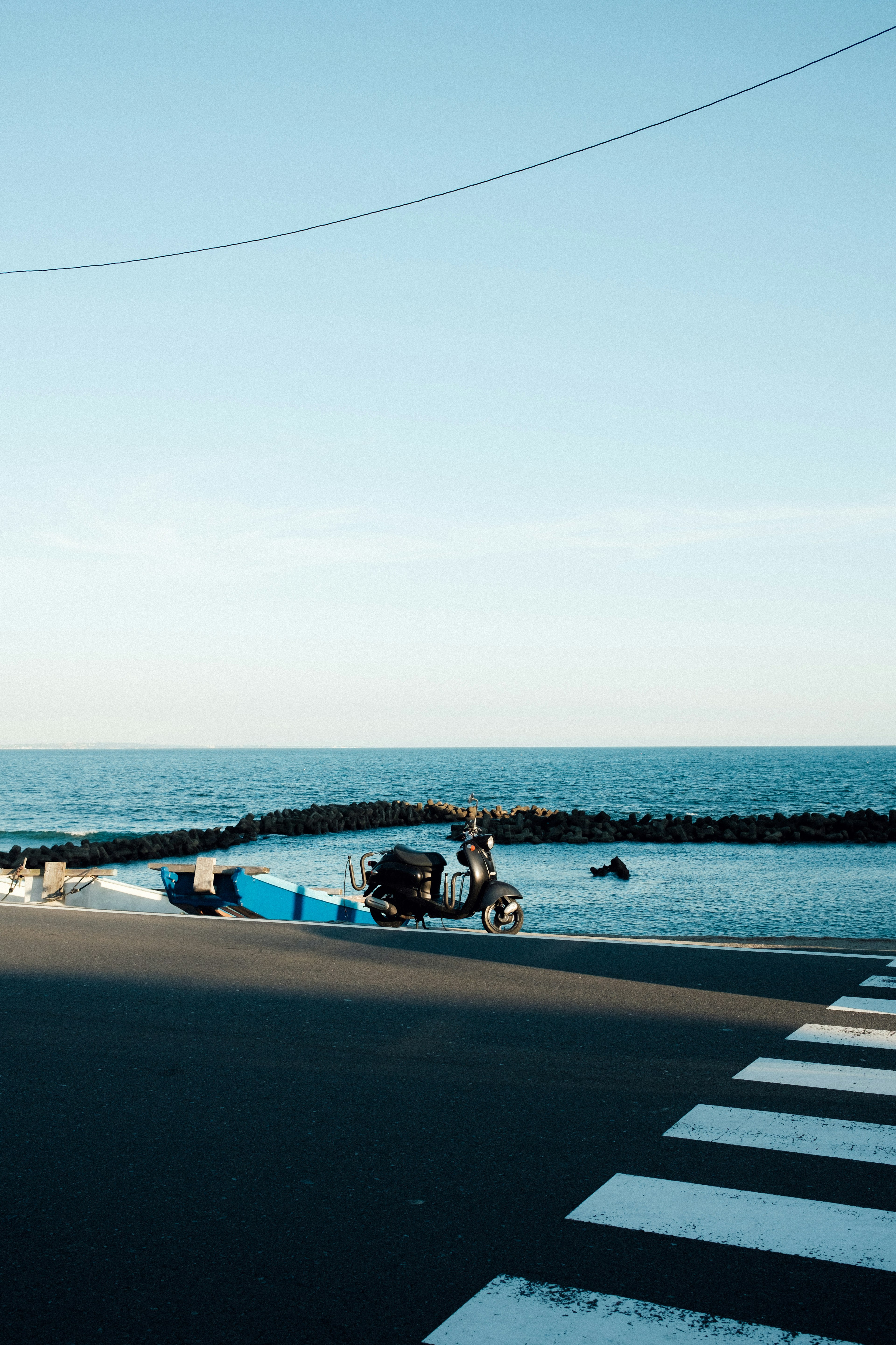 Scenic view with blue sea and crosswalk featuring a person fishing