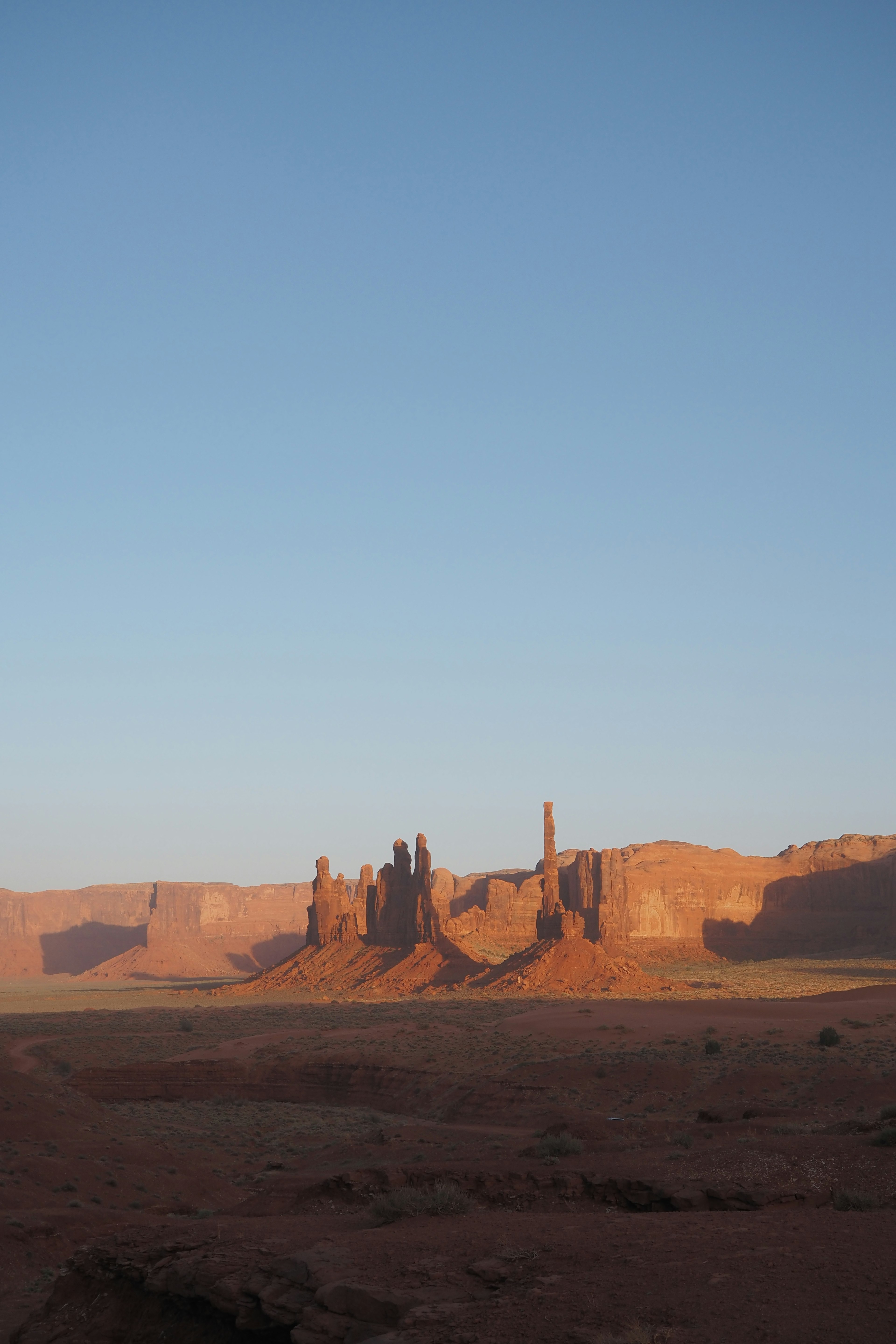 Vast desert landscape with red rock formations and a blue sky