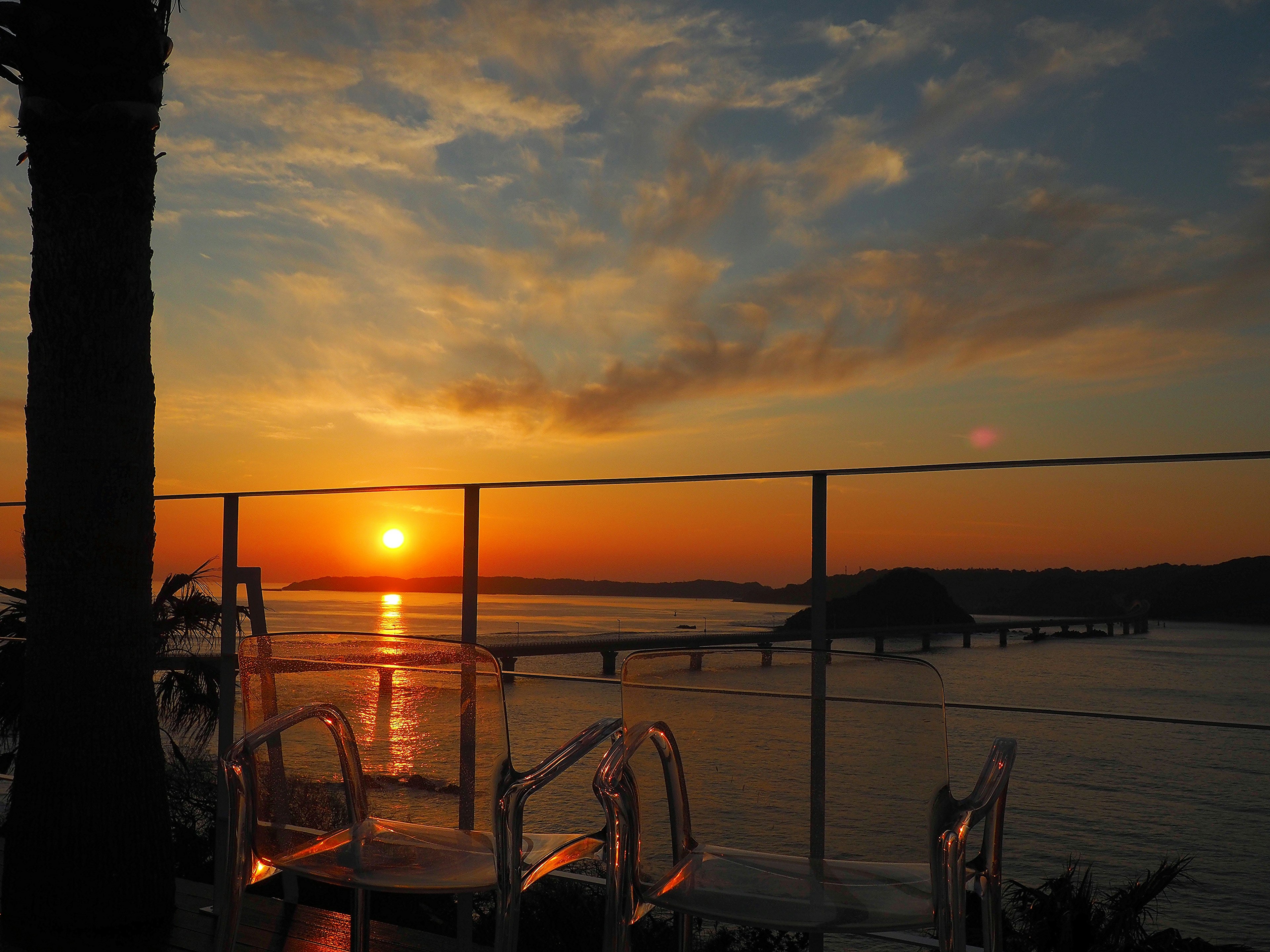 Bellissimo tramonto sull'oceano con un ponte e sedie trasparenti