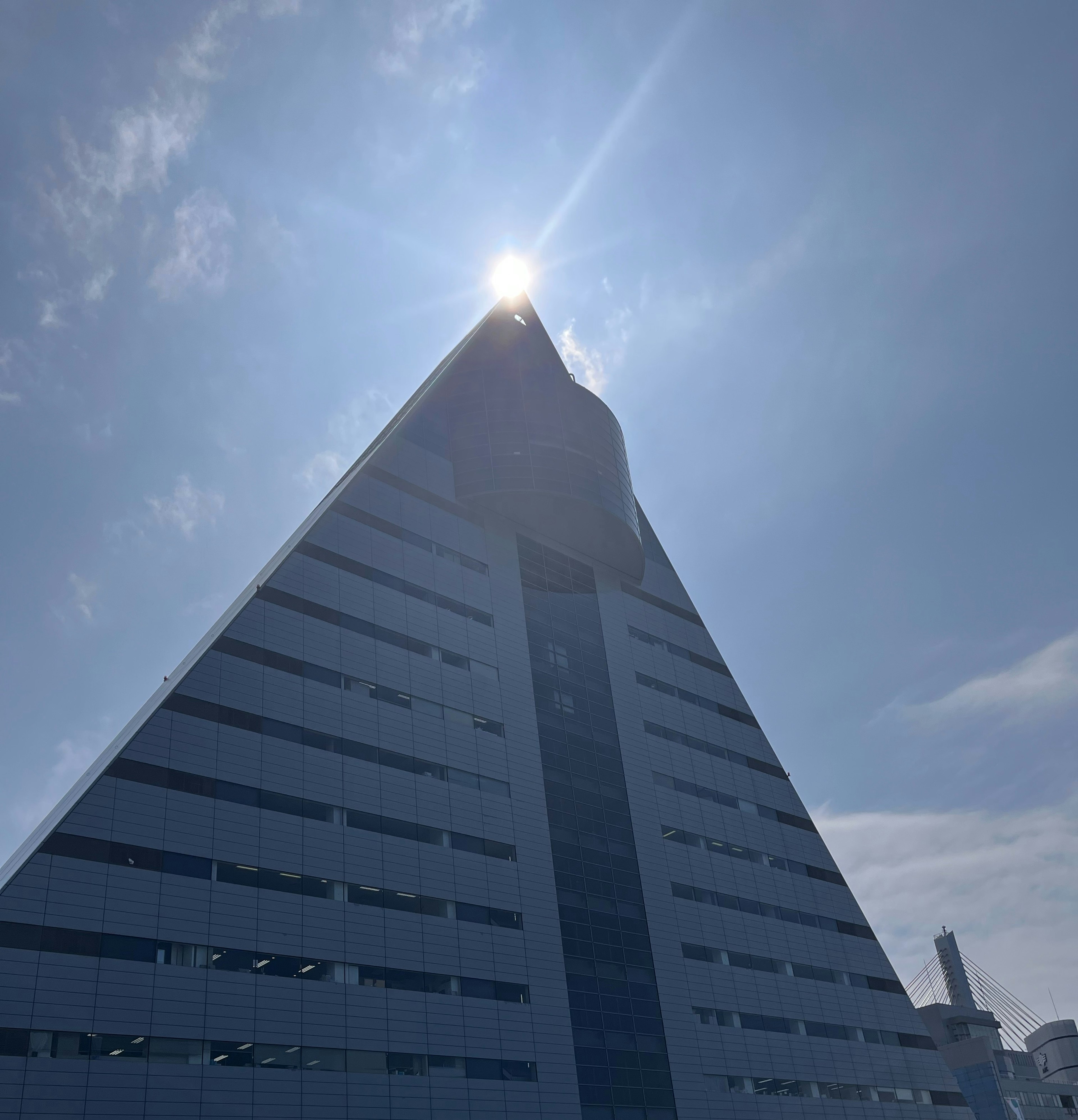 A modern pyramid-shaped building towering under a blue sky