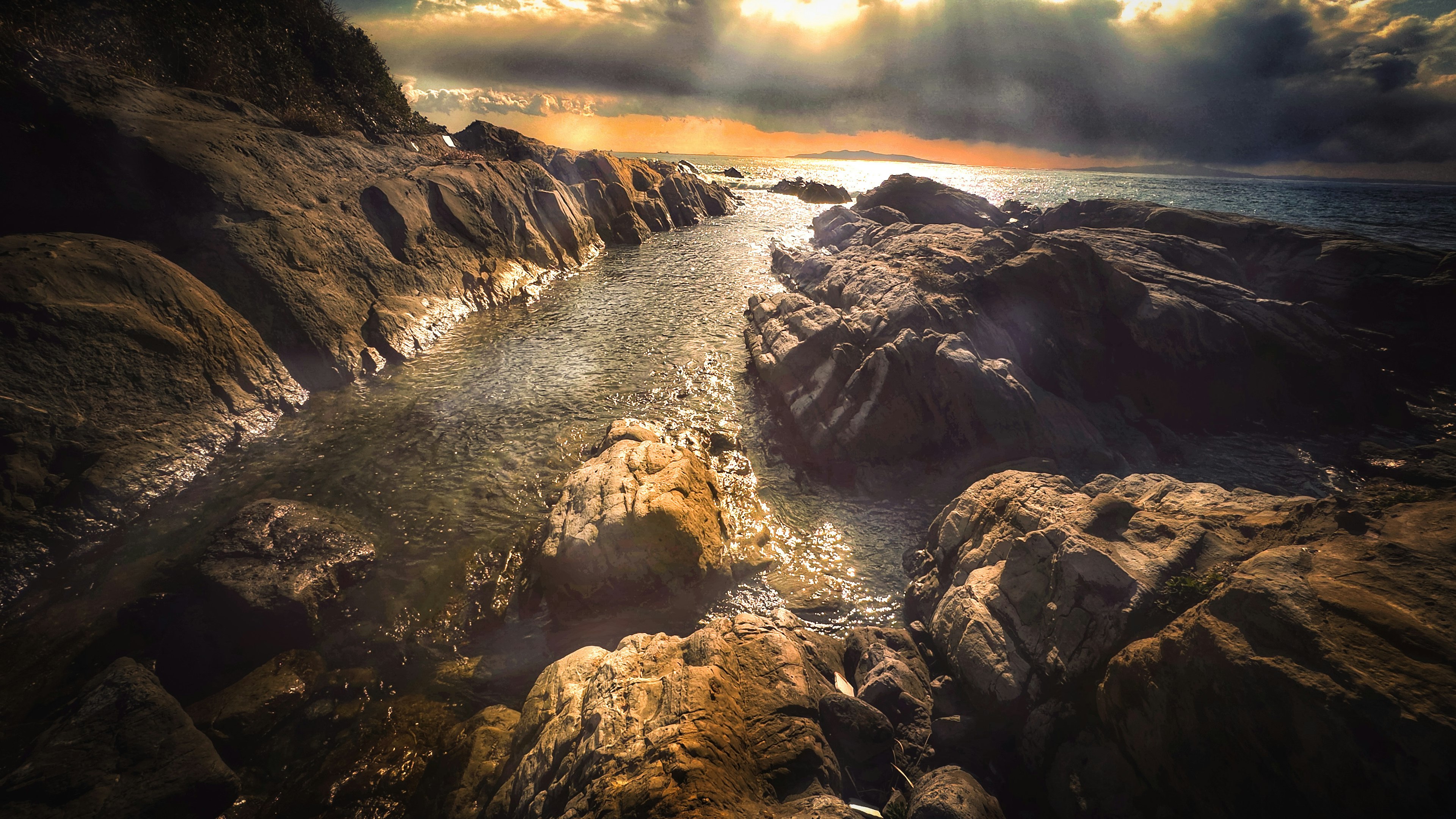 Scenic view of water flowing between rocks with a dramatic sky