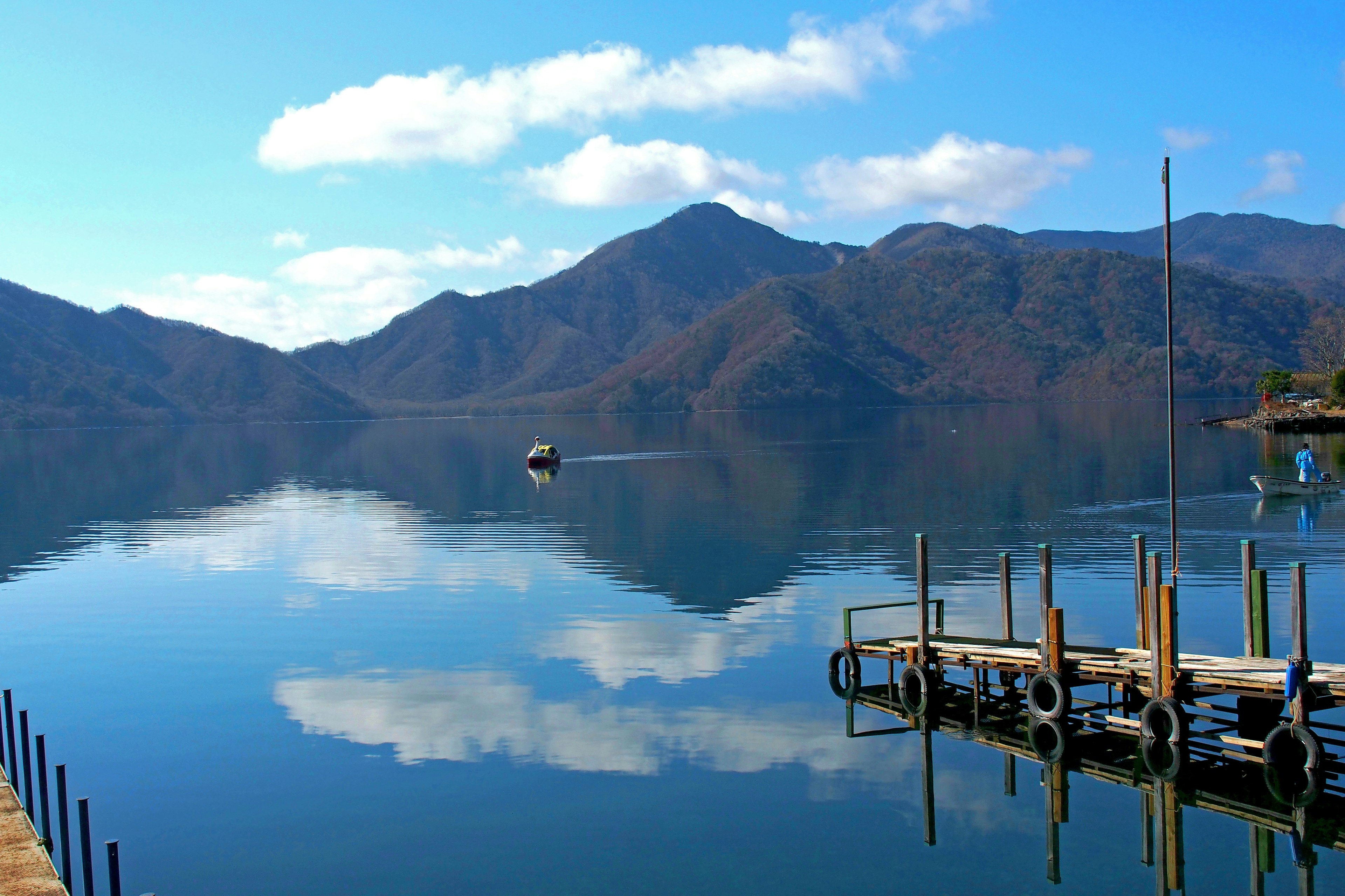 Vista serena del lago con una barca e riflessi delle montagne