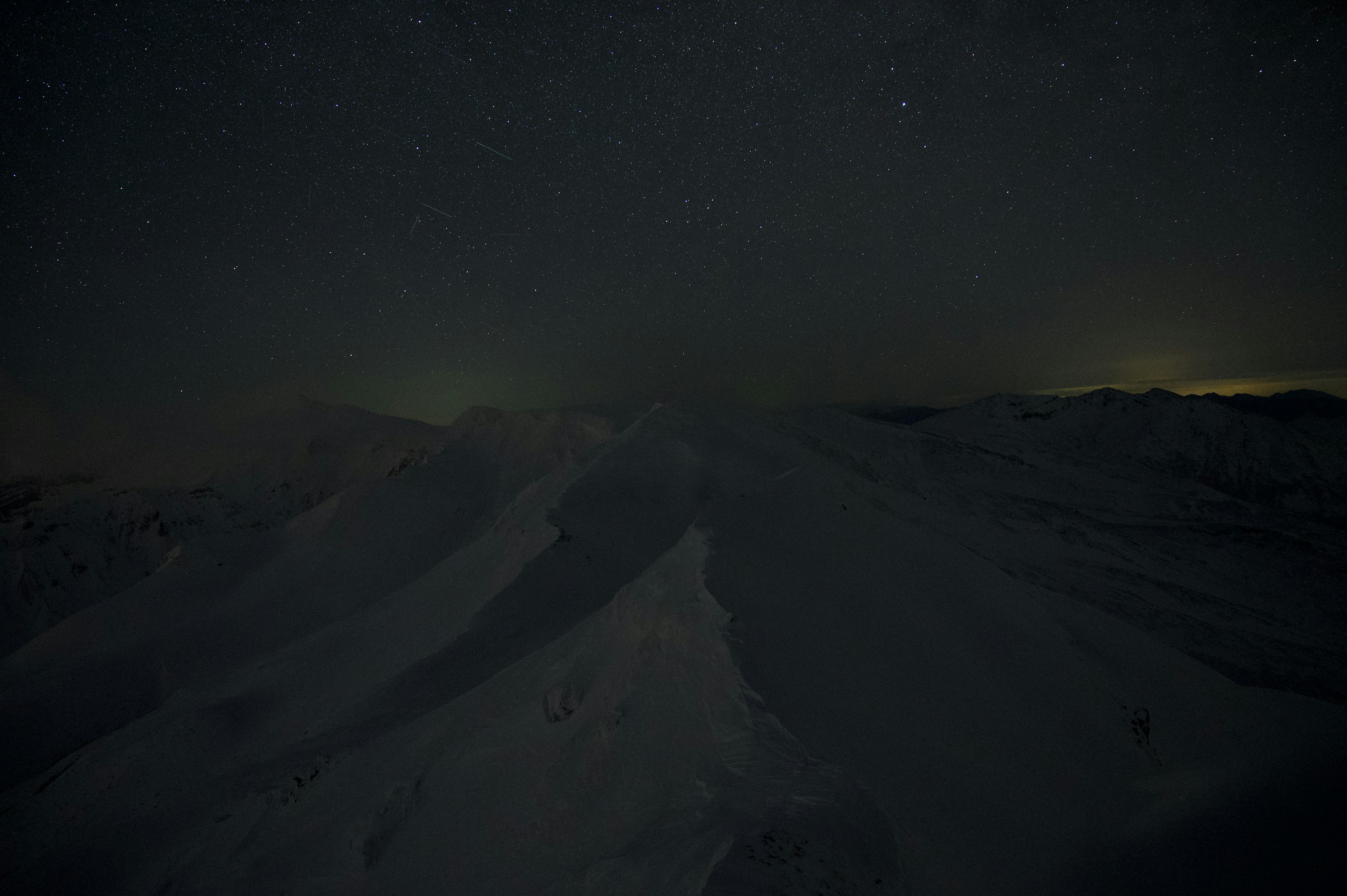 暗い夜空に星々が輝く雪山の風景