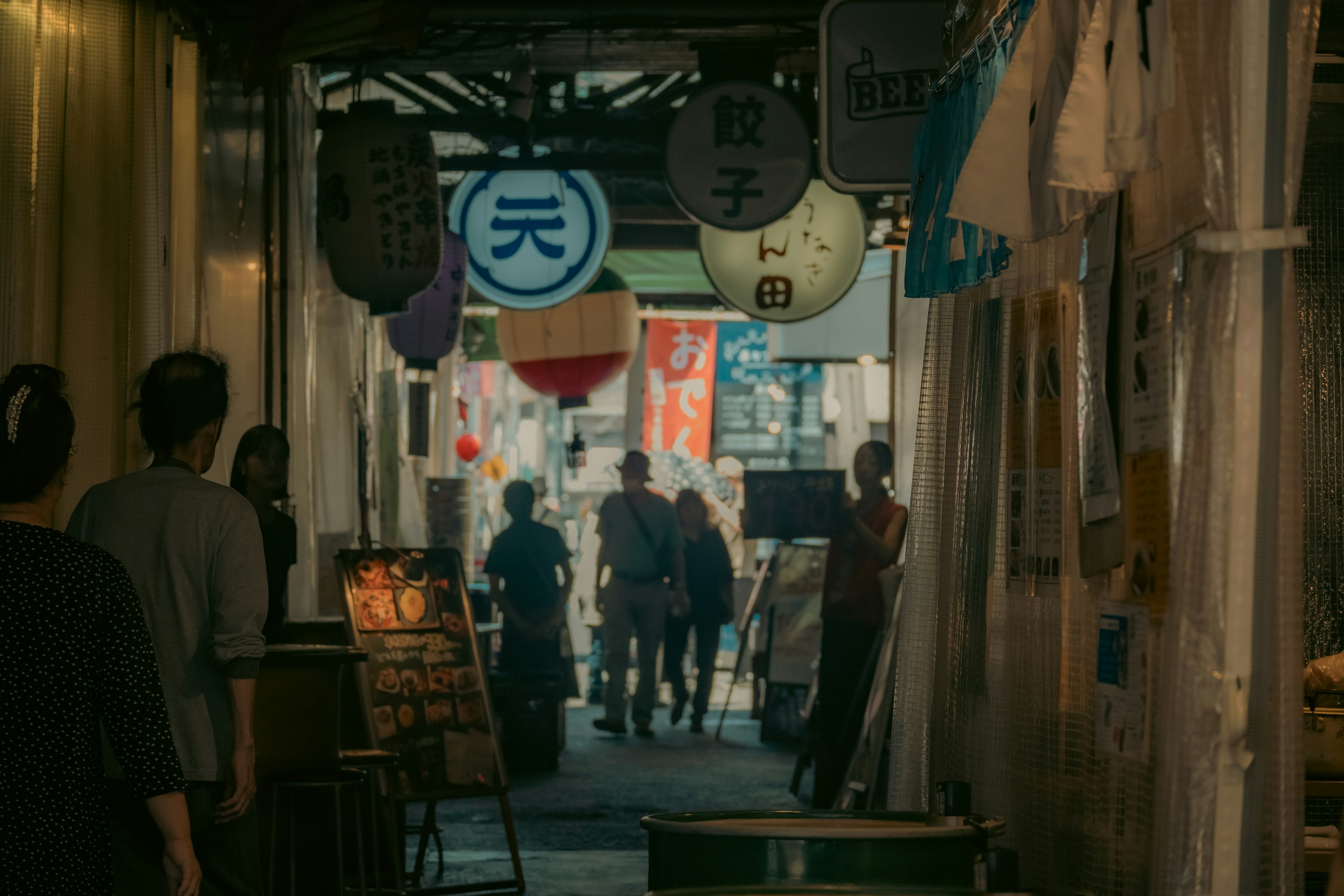 Bustling arcade scene with people walking through illuminated lanterns and banners lining the street